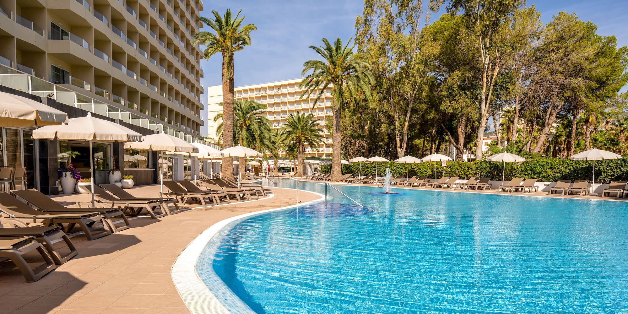 a pool with umbrellas and chairs in front of a building