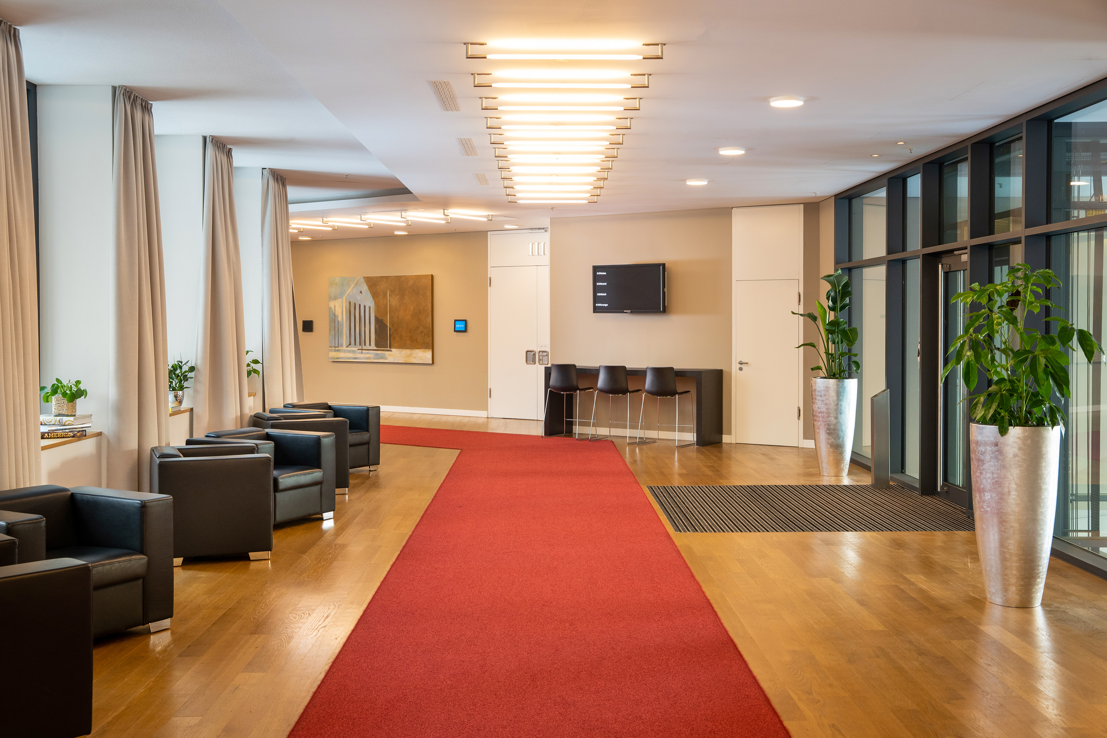 Modern office lobby with red carpet, black chairs, and reception area.