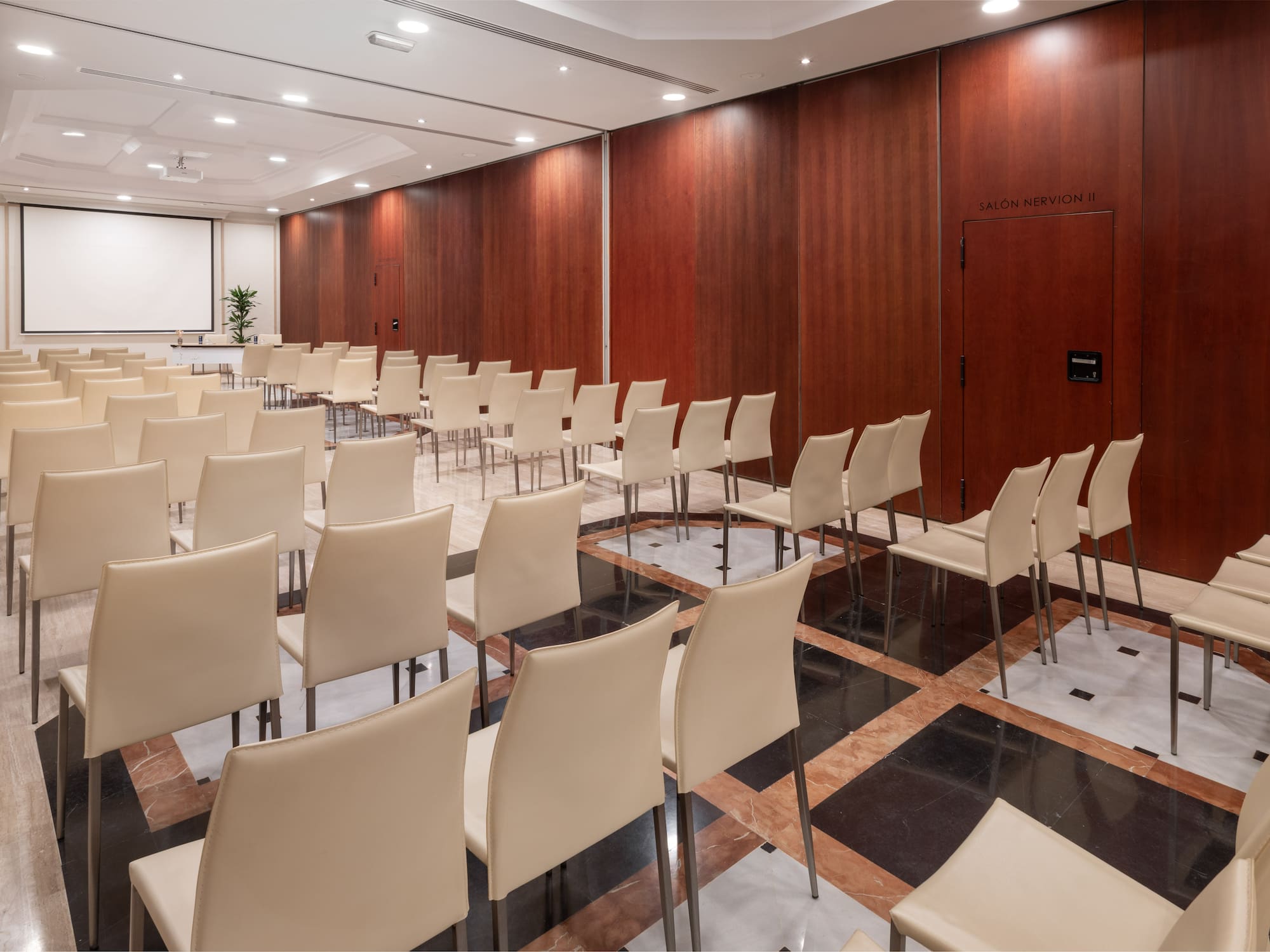 a room with white chairs and a wood paneled wall