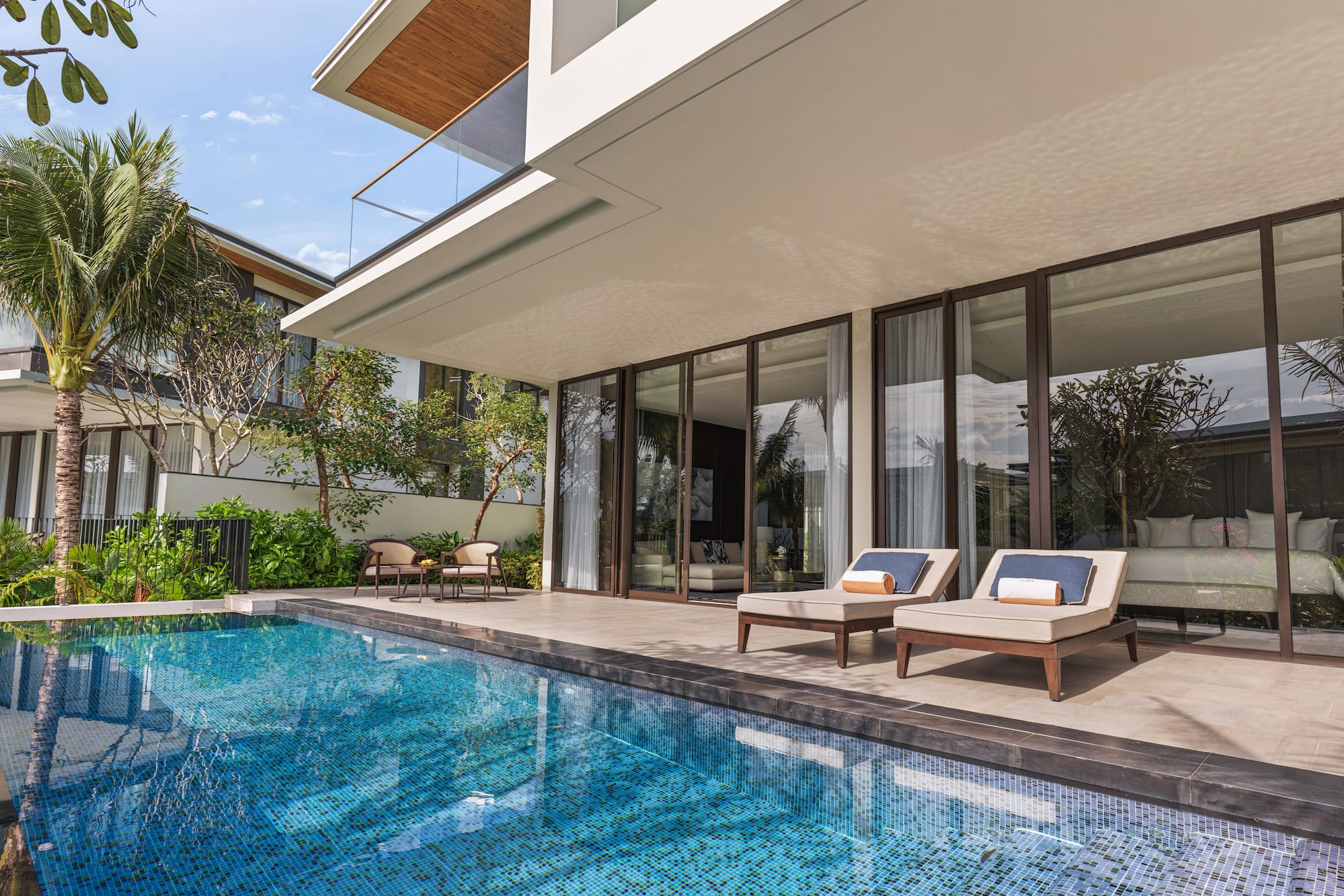 a pool with chairs and a deck chair in front of a house
