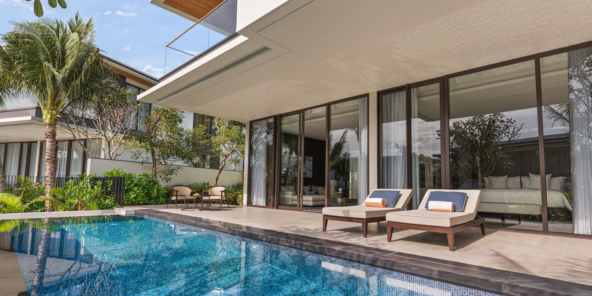 a pool with chairs and a deck chair in front of a house