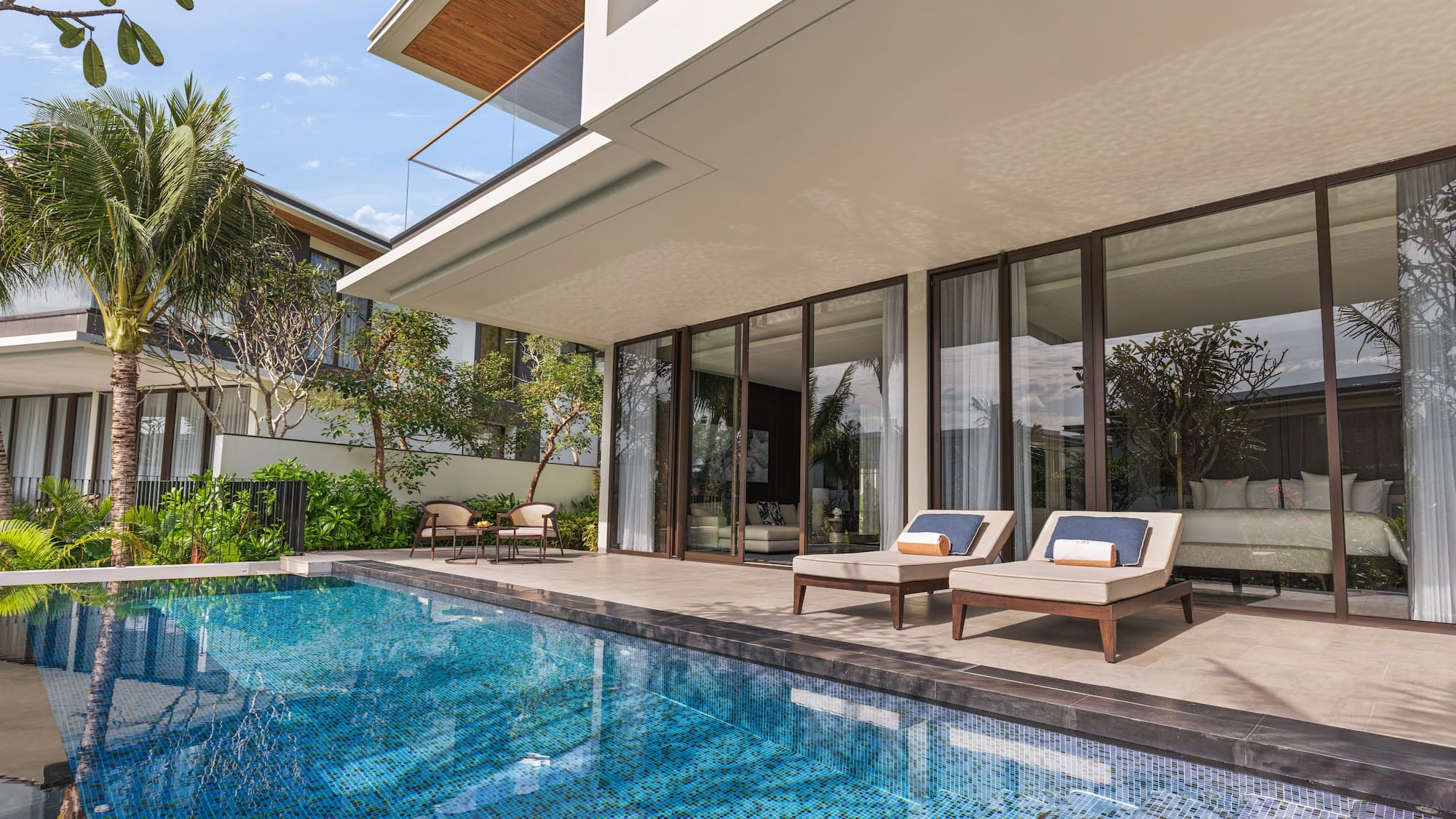 a pool with chairs and a deck chair in front of a house