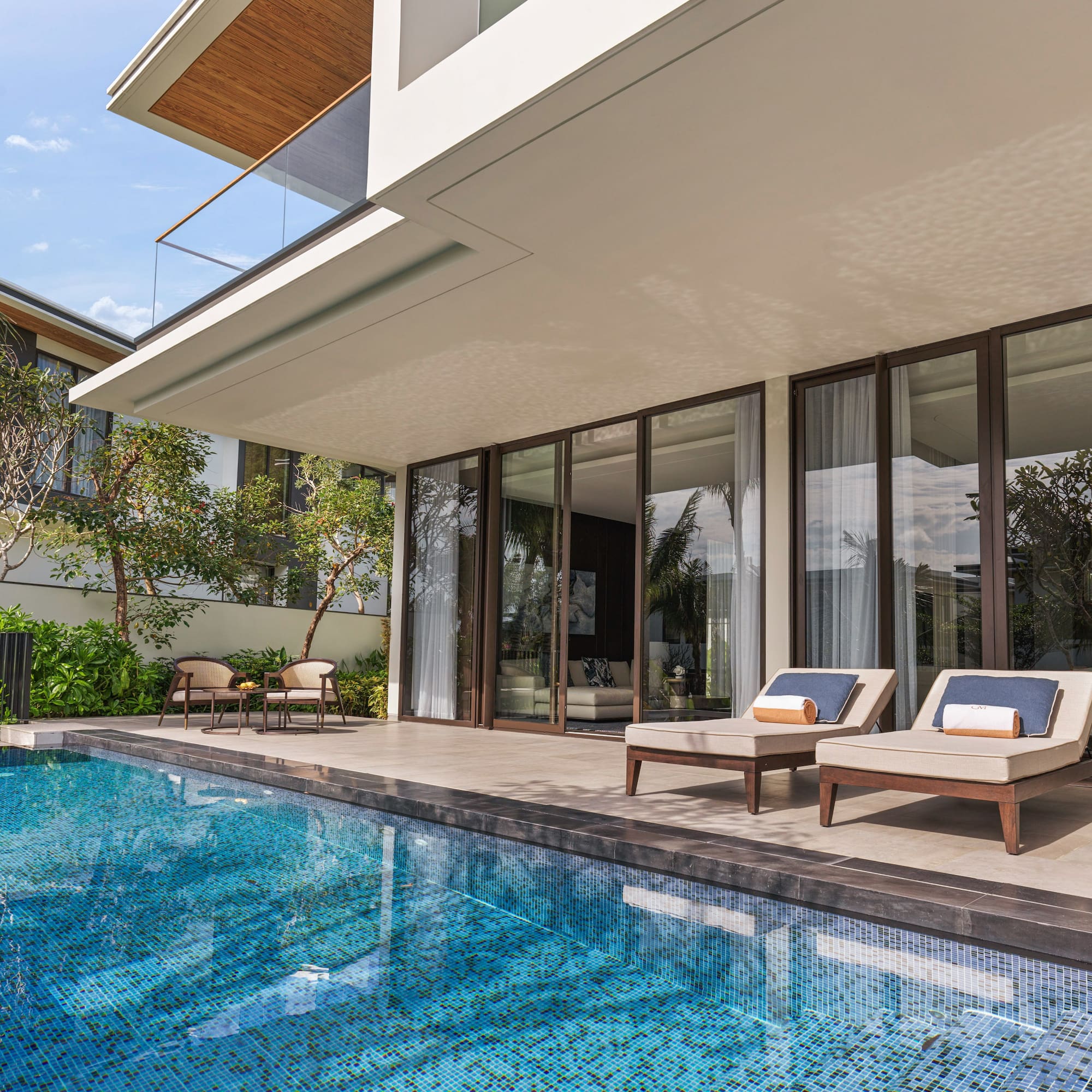 a pool with chairs and a deck chair in front of a house
