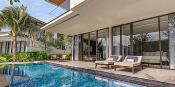 a pool with chairs and a deck chair in front of a house