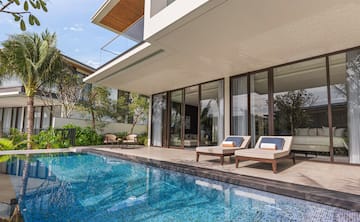 a pool with chairs and a deck chair in front of a house