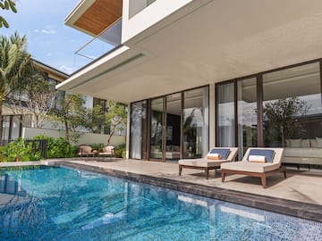 a pool with chairs and a deck chair in front of a house