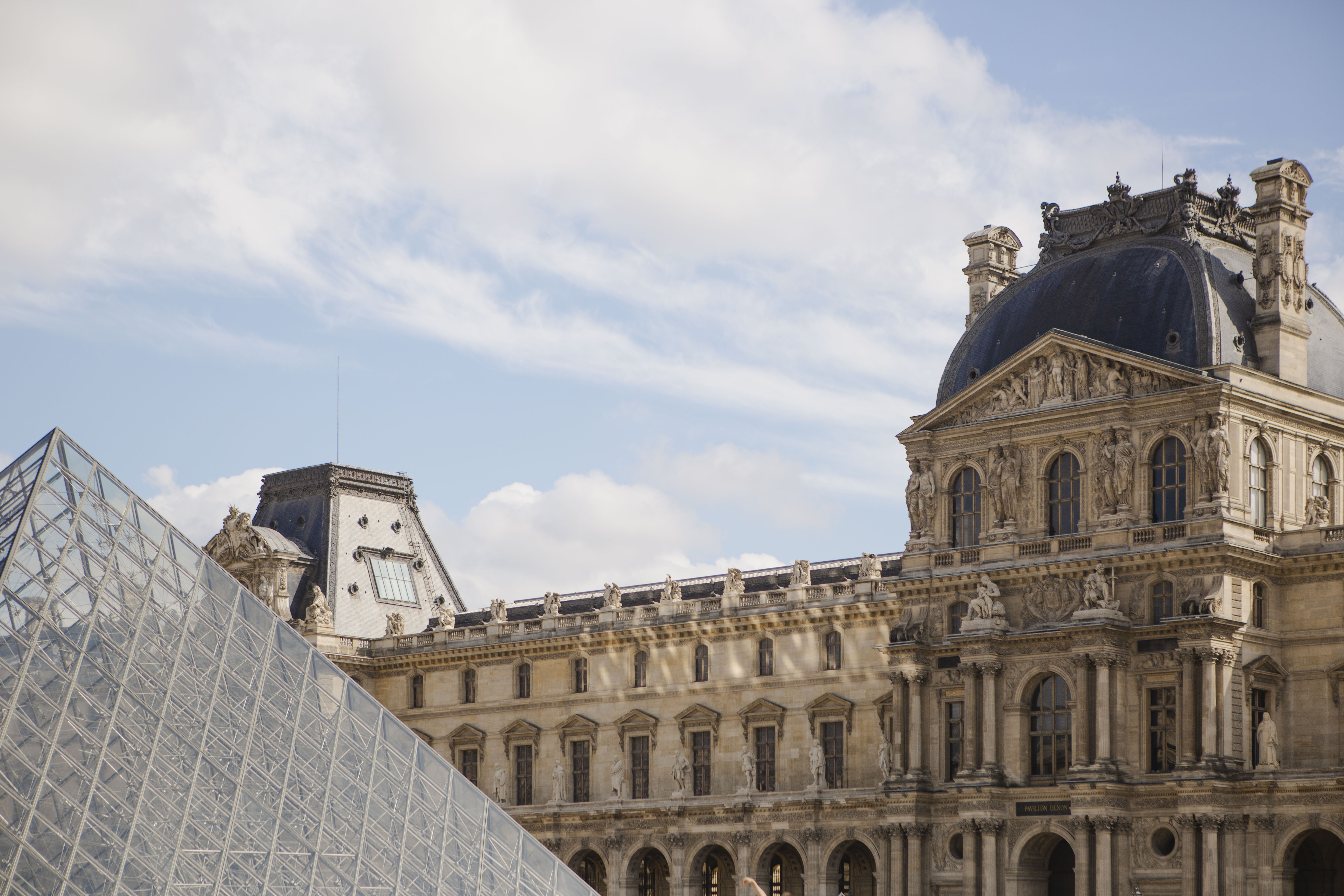 Louvre Museum, Paris: glass pyramid next to ornate classical architecture.