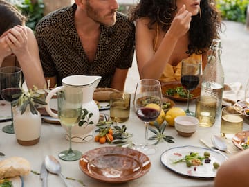 a group of people sitting at a table with food and drinks