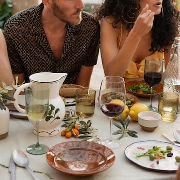 a group of people sitting at a table with food and drinks