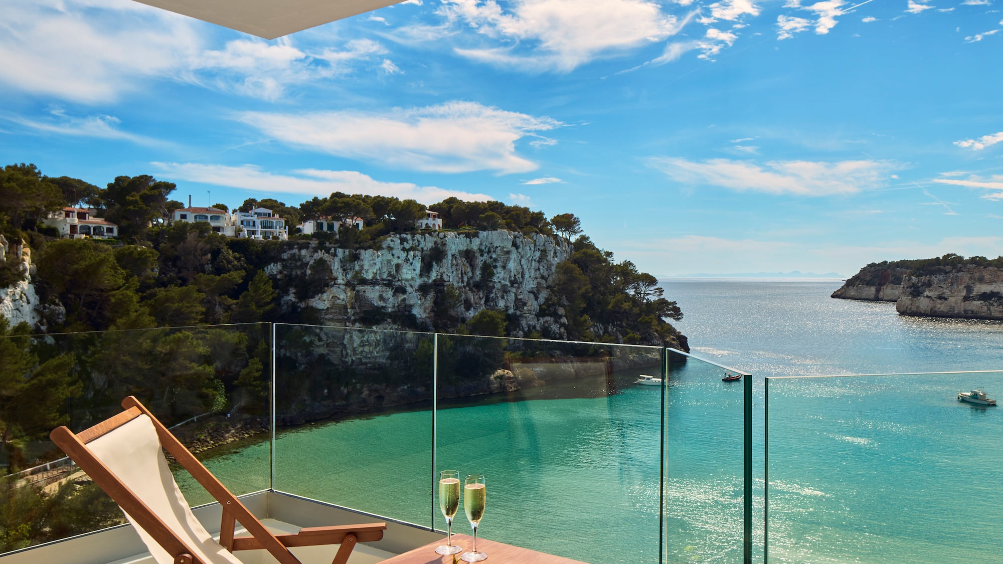 a table with two glasses of champagne on it overlooking a body of water