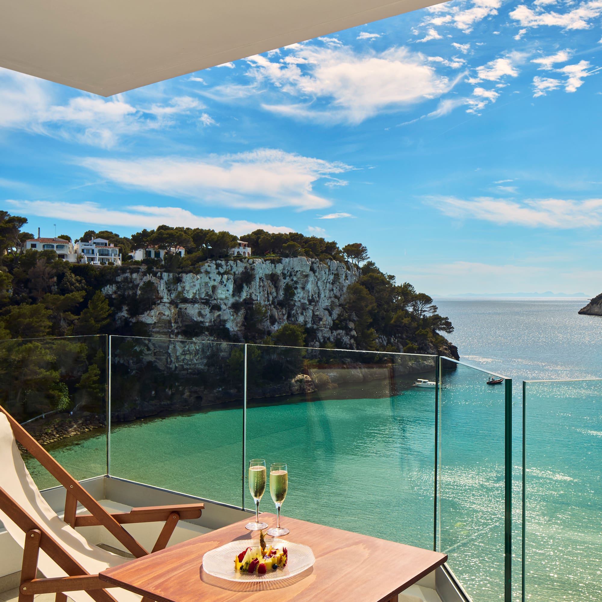 a table with two glasses of champagne on it overlooking a body of water