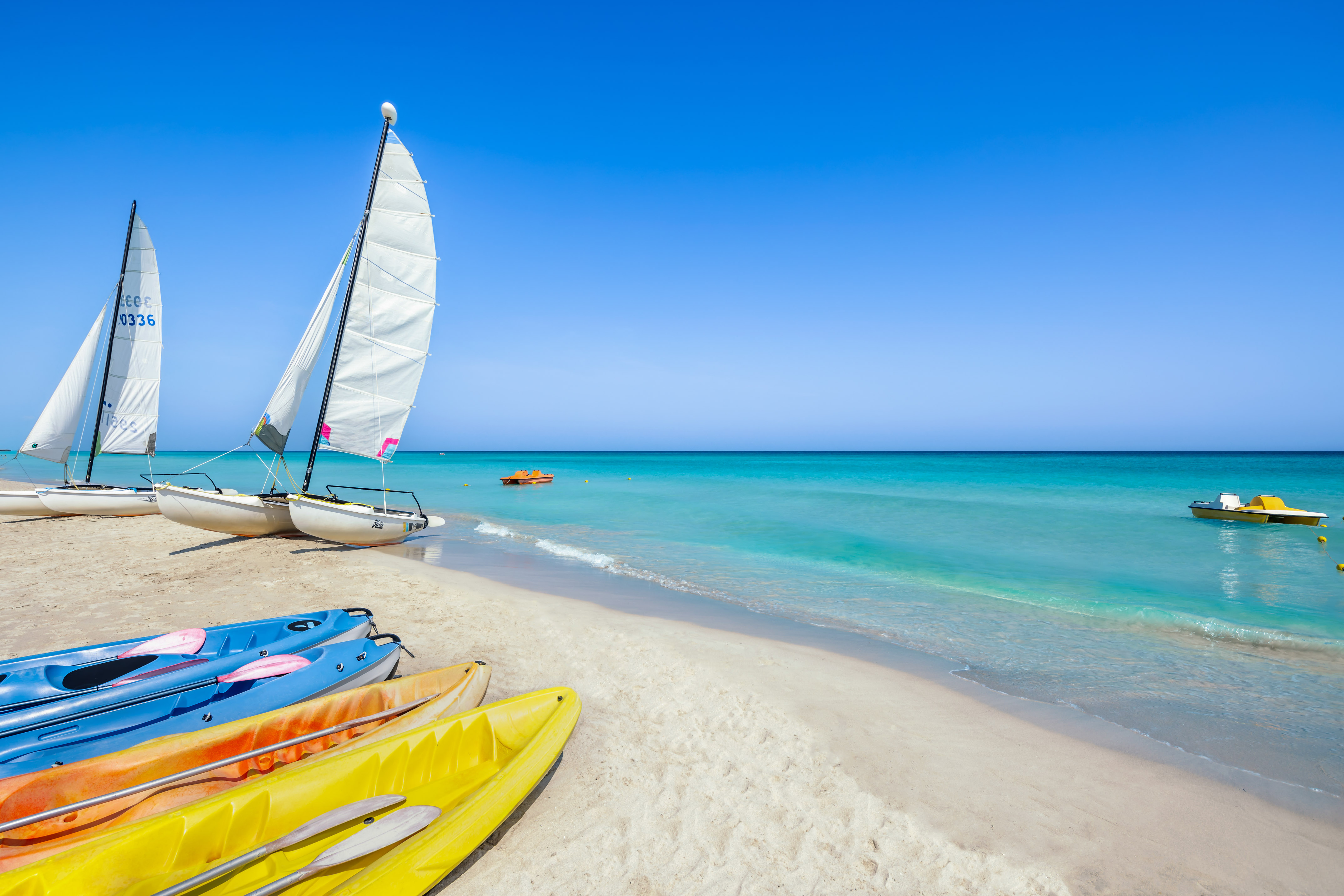 a sailboat and kayaks on a beach