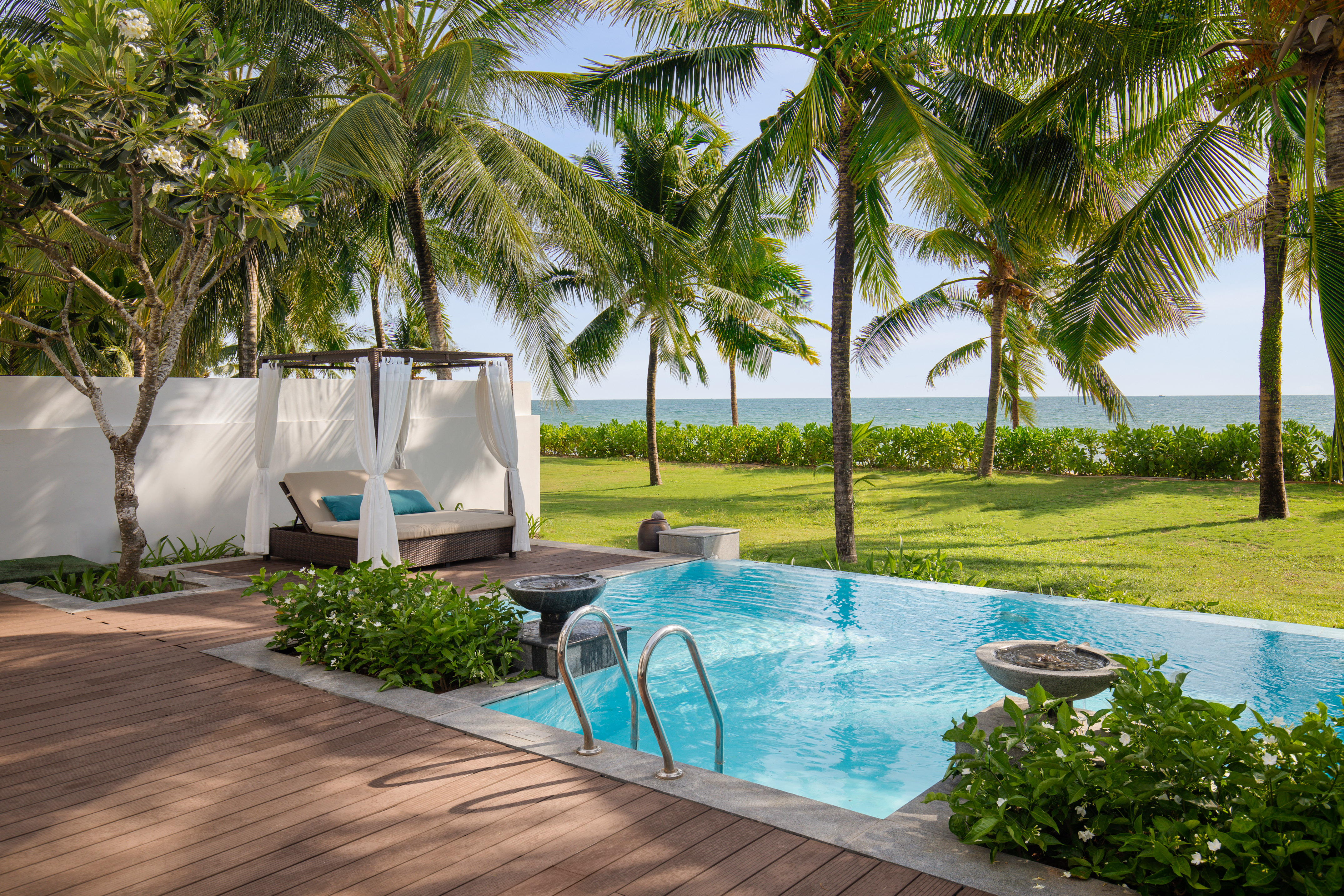 Luxury private pool with cabana, palm trees, and ocean view.