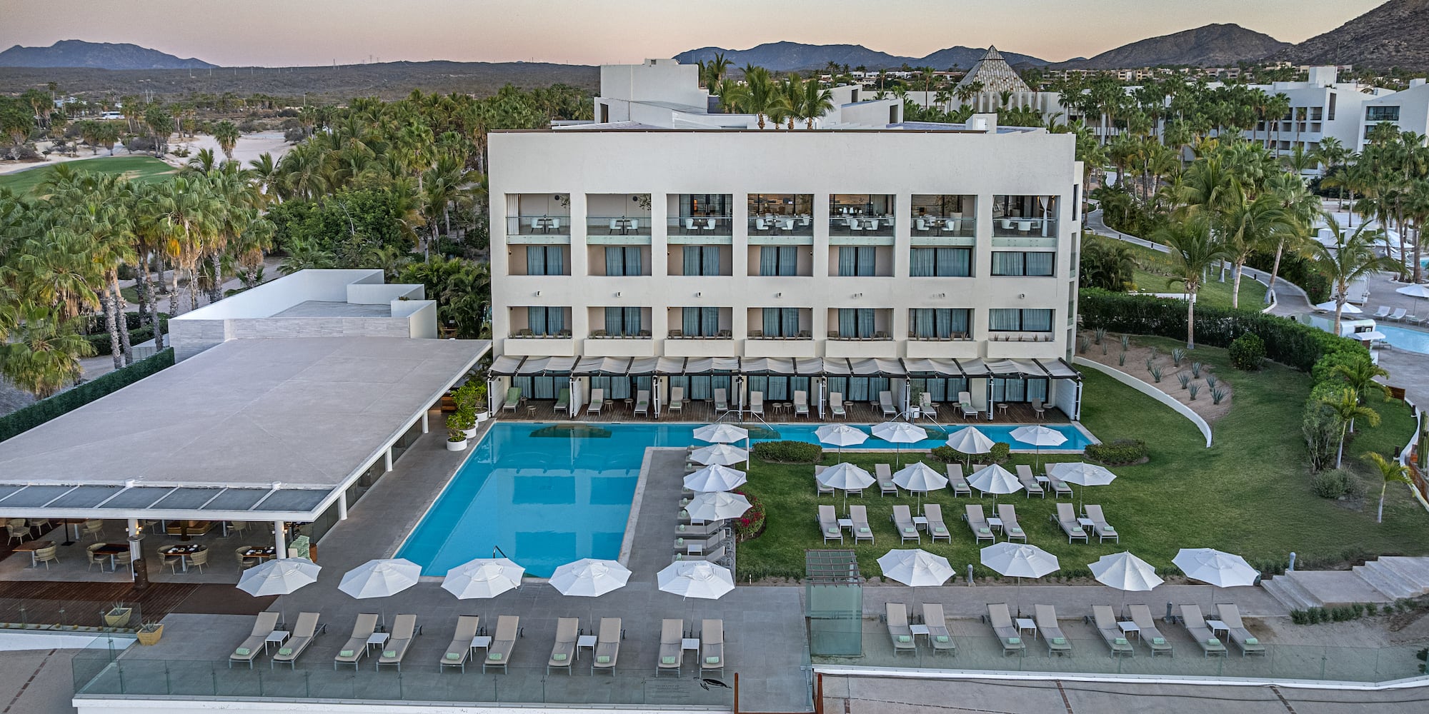 a pool and lounge chairs in front of a building