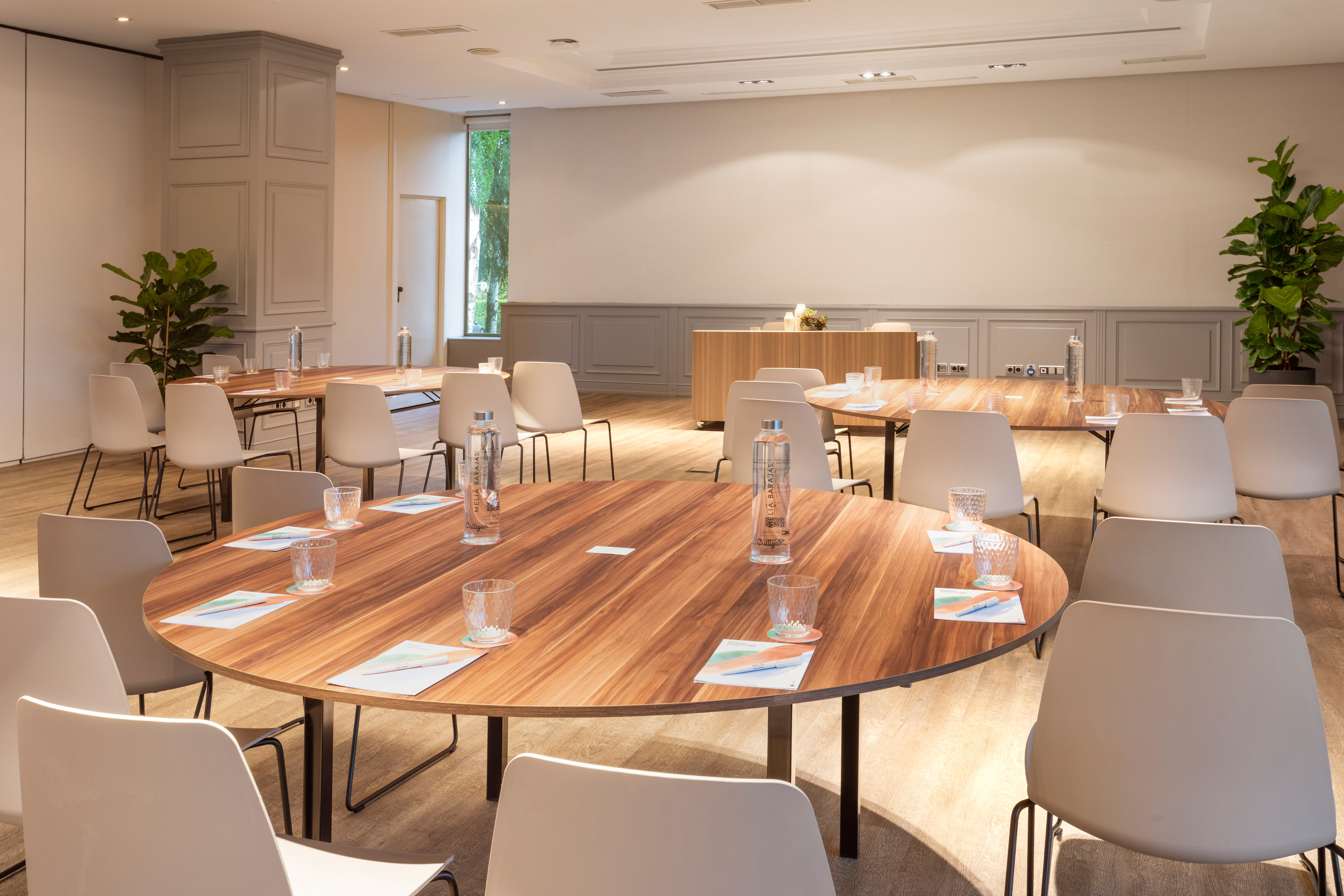 Modern meeting room with wooden tables, neutral chairs, and natural light.