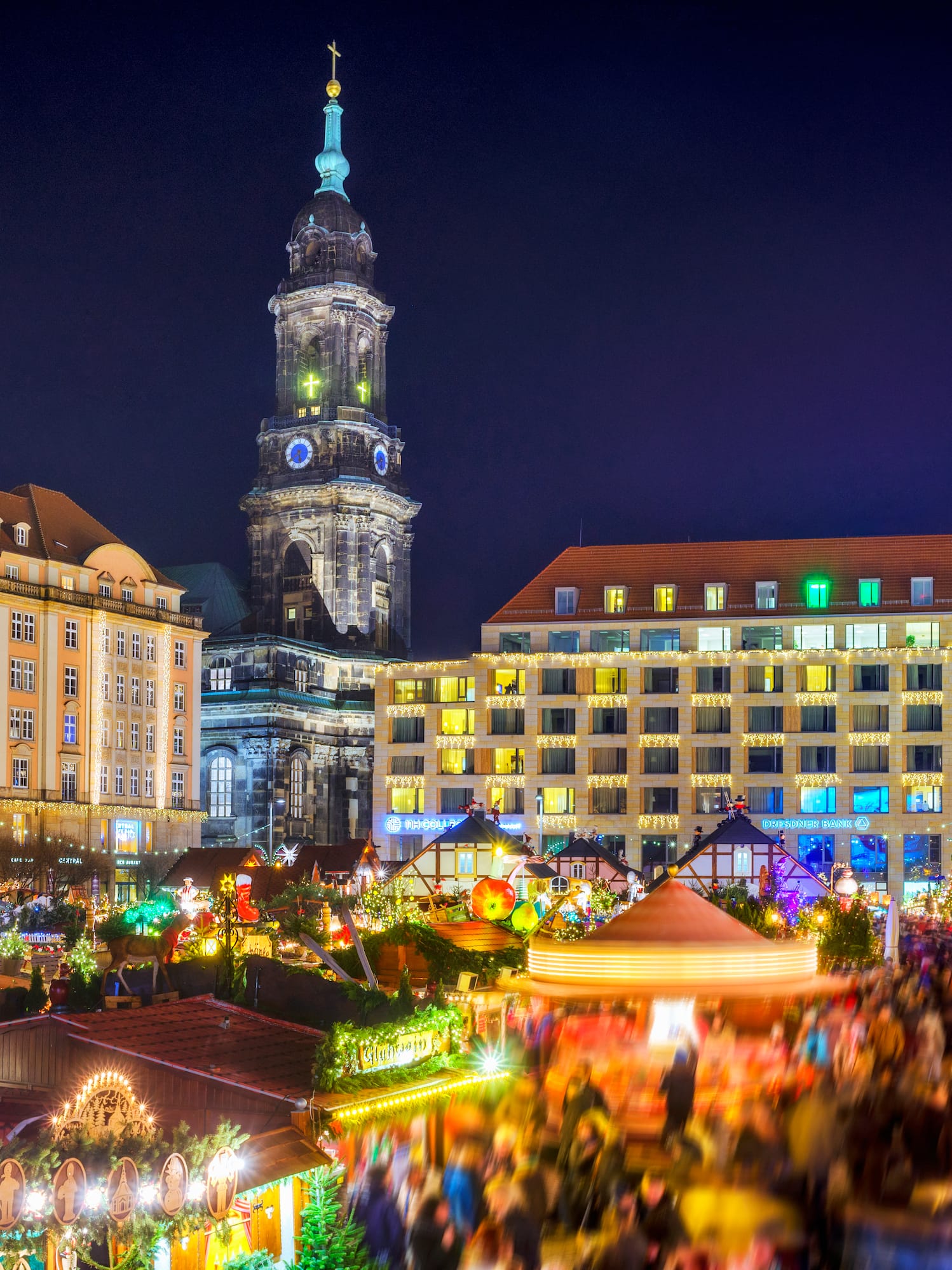 Dresden Striezelmarkt at night with illuminated tree, pyramid, and church tower.