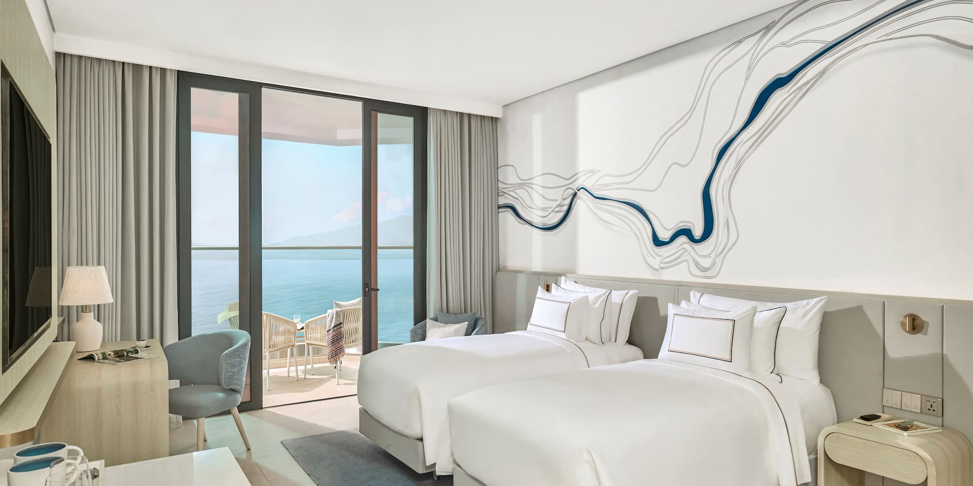 Modern ocean view hotel room with twin beds and private balcony.