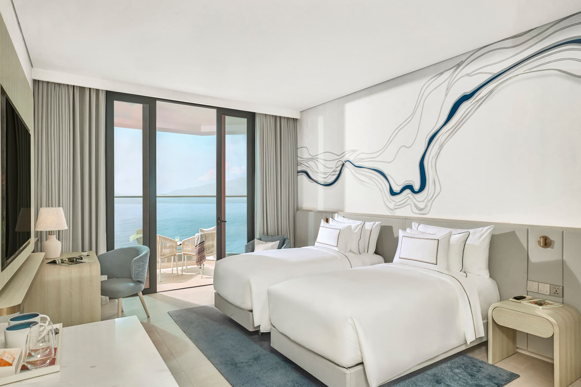 Modern ocean view hotel room with twin beds and private balcony.