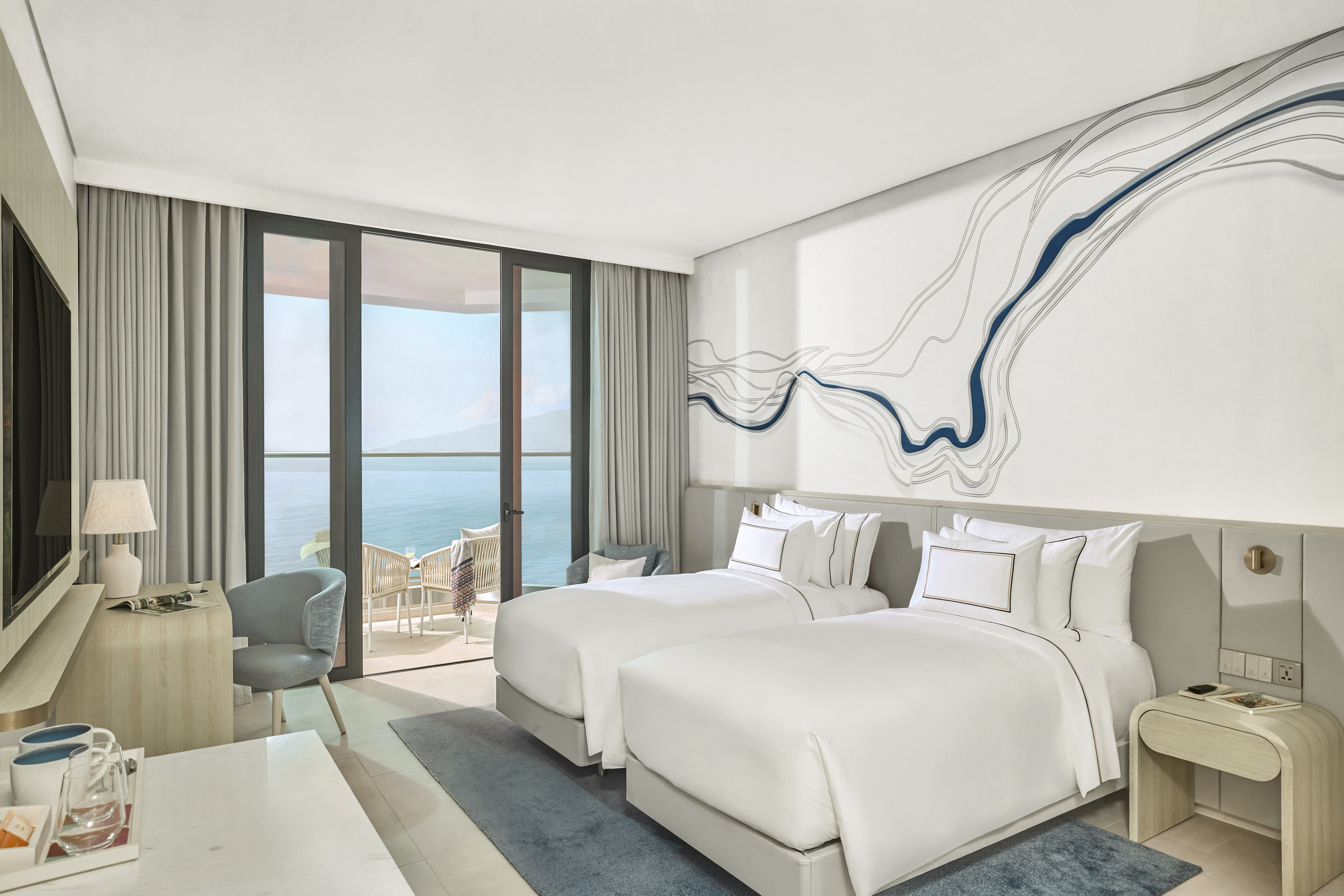 Modern ocean view hotel room with twin beds and private balcony.