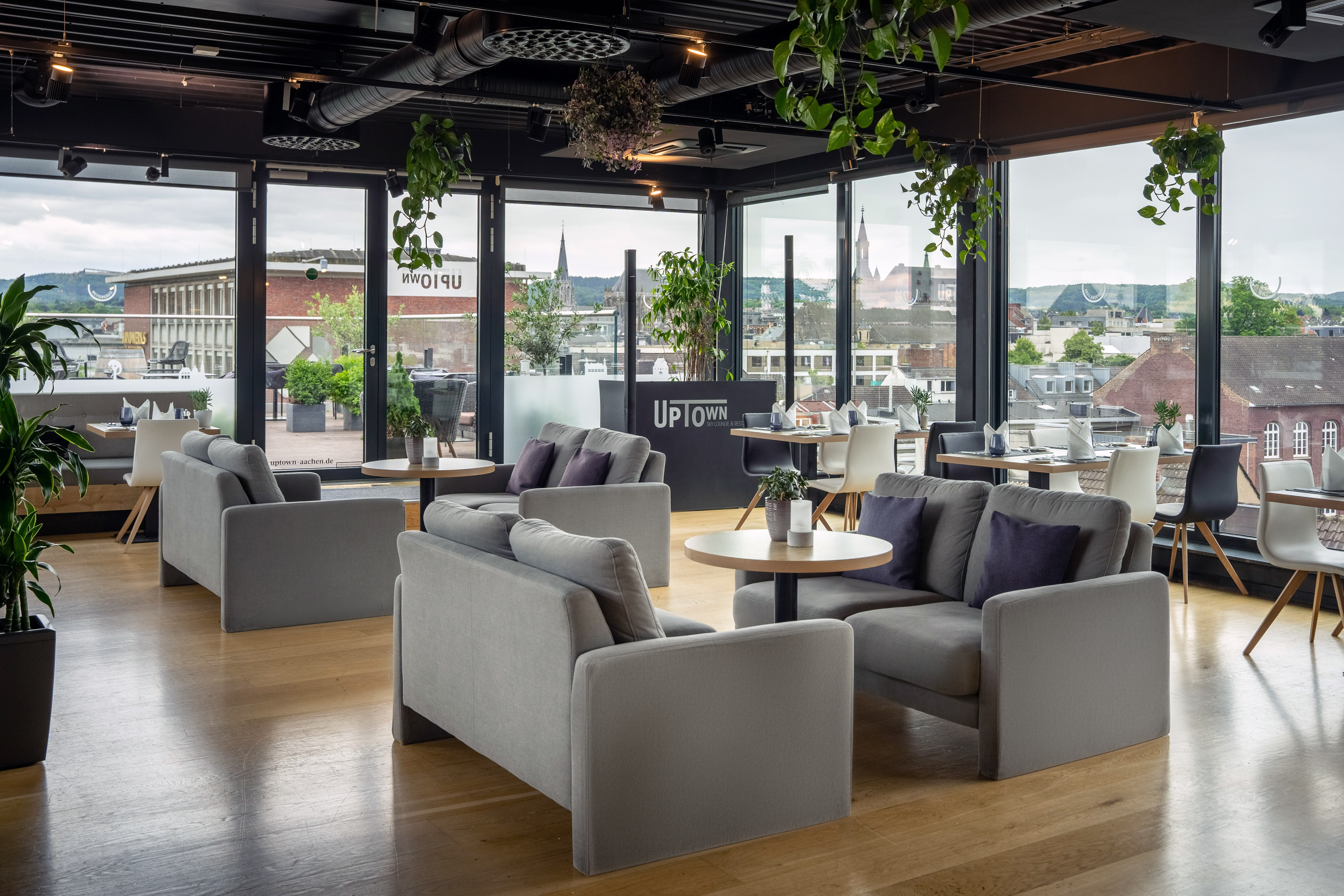 UPTOWN Sky Lounge in Aachen with modern seating, plants, and city skyline.
