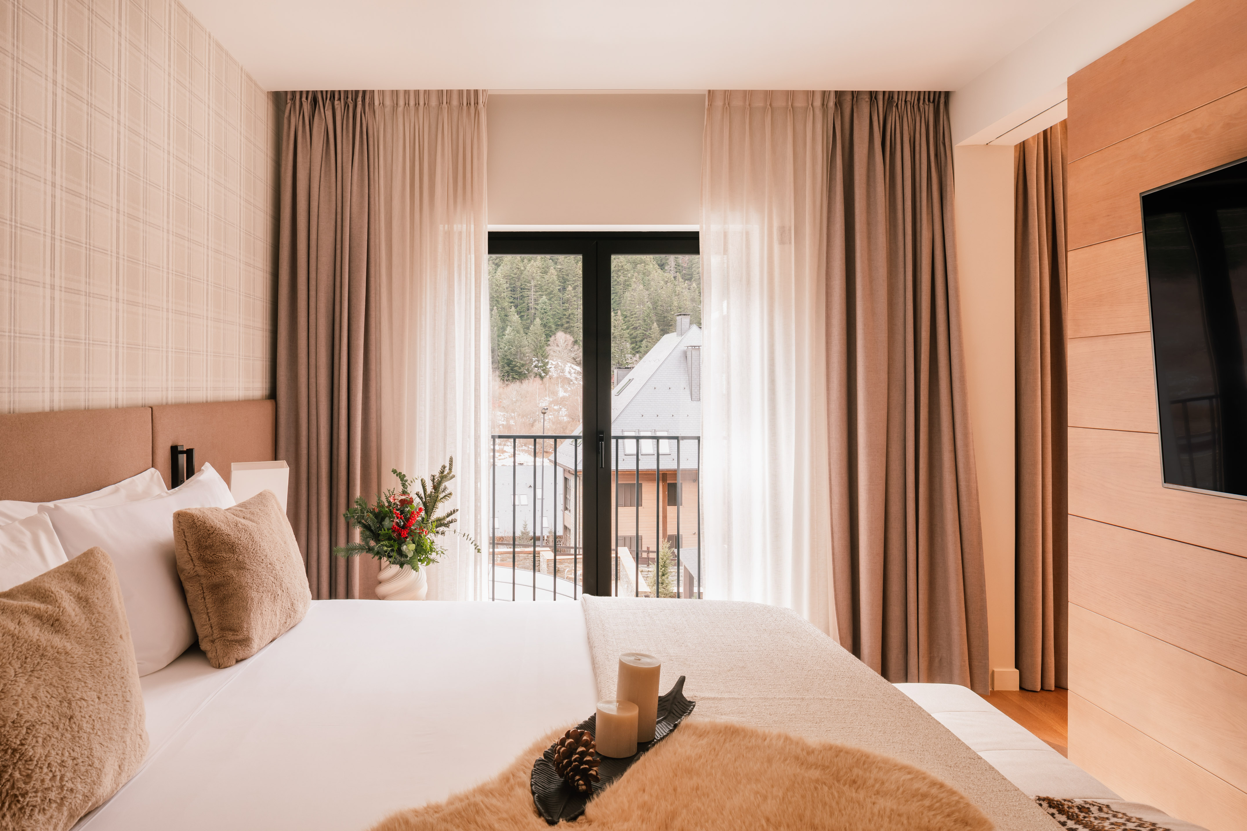 Modern hotel room with mountain view balcony, soft bed, and winter details.