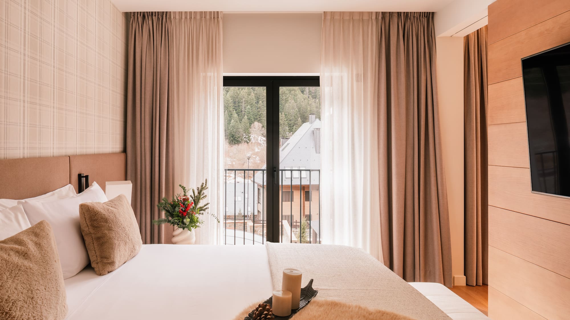 Modern hotel room with mountain view balcony, soft bed, and winter details.