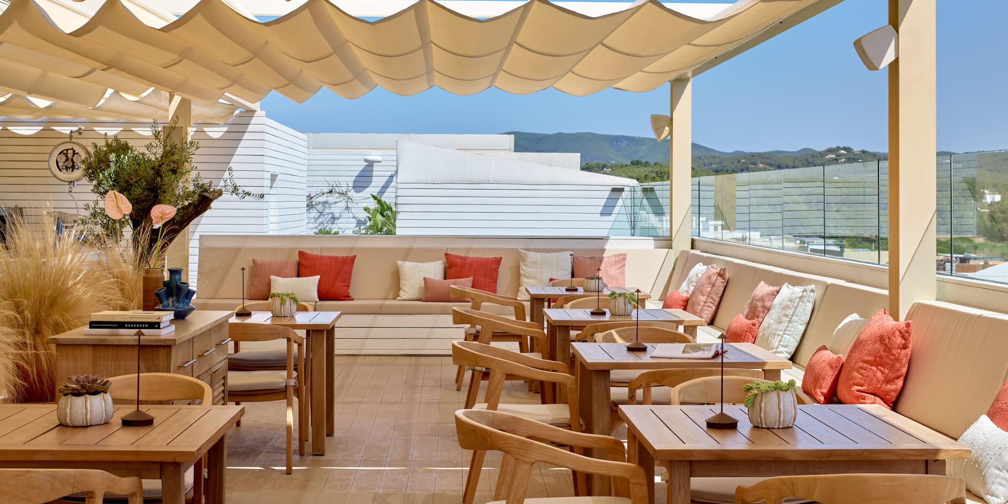 Outdoor dining terrace with shaded canopy, wooden tables, and scenic views.