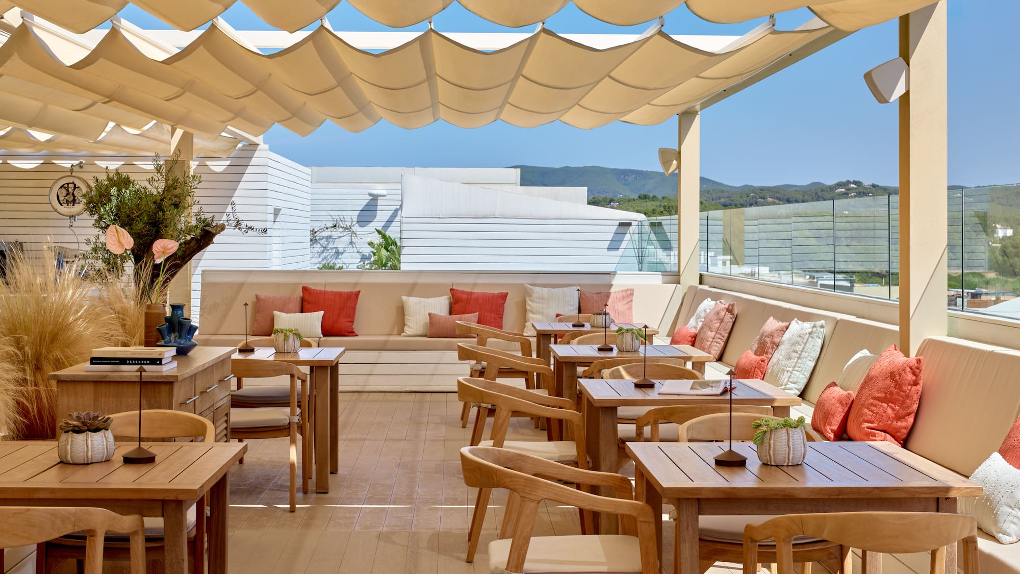 Outdoor dining terrace with shaded canopy, wooden tables, and scenic views.