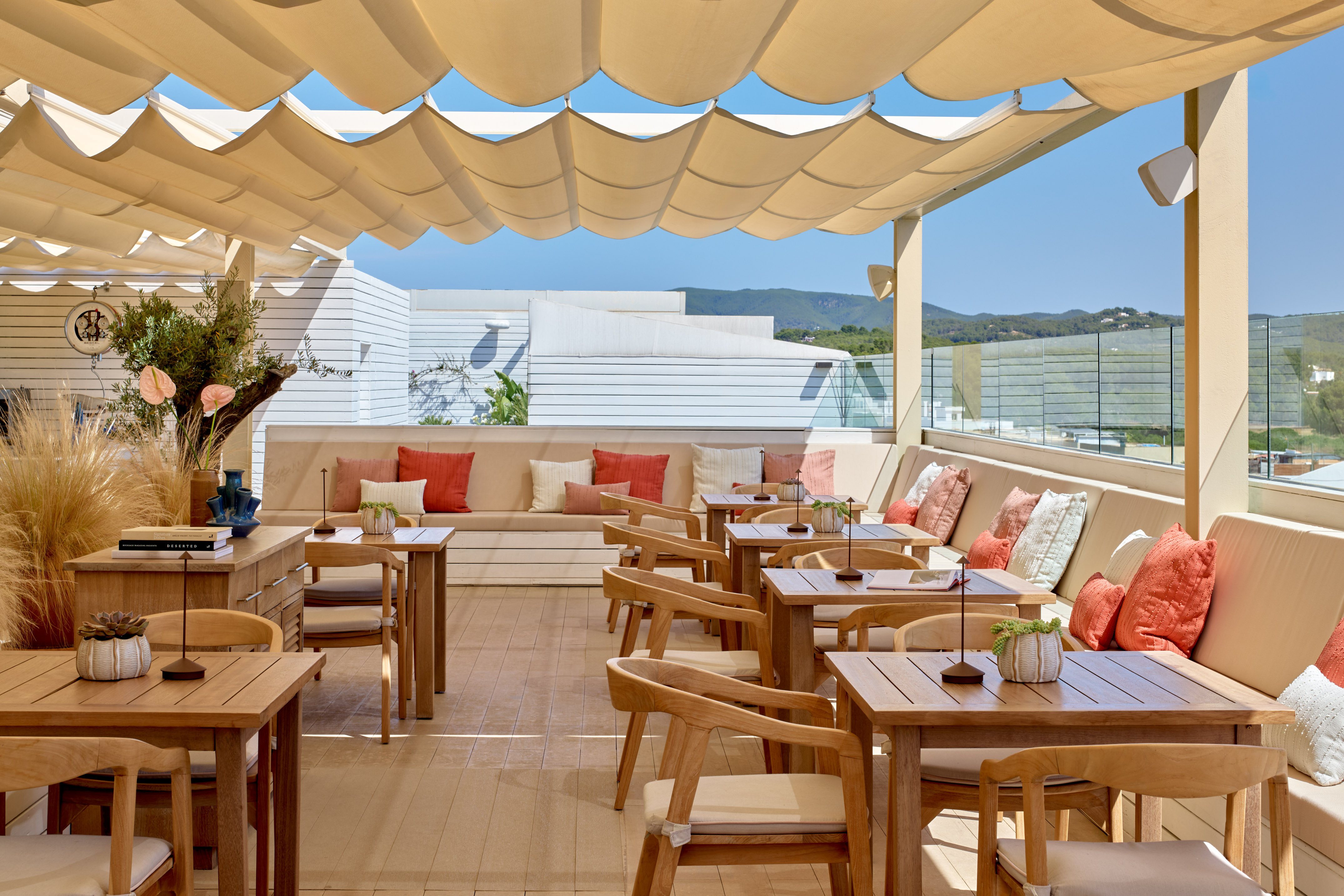 Outdoor dining terrace with shaded canopy, wooden tables, and scenic views.