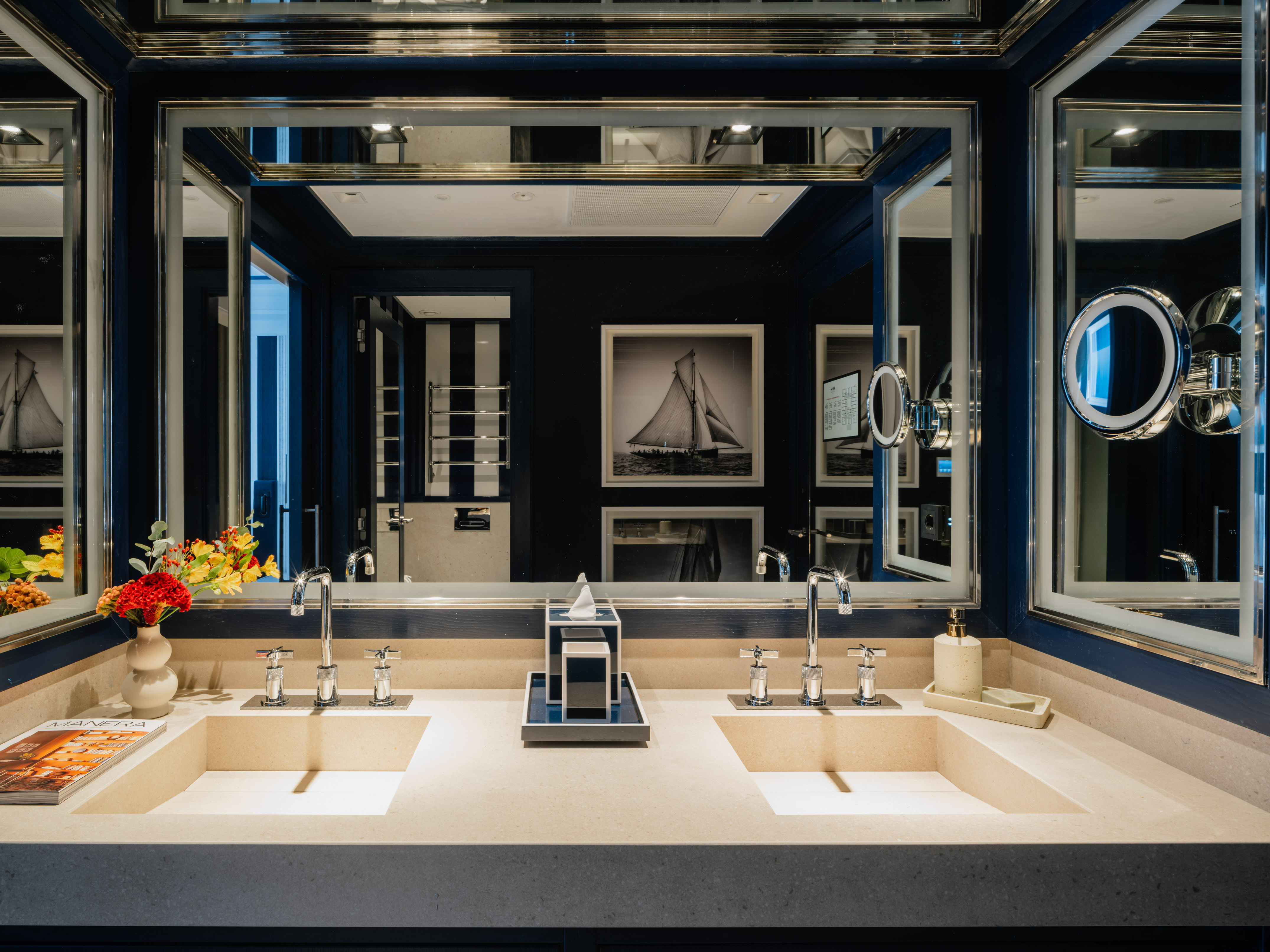Stylish navy blue bathroom with double vanity, mirrors, and sailboat artwork.