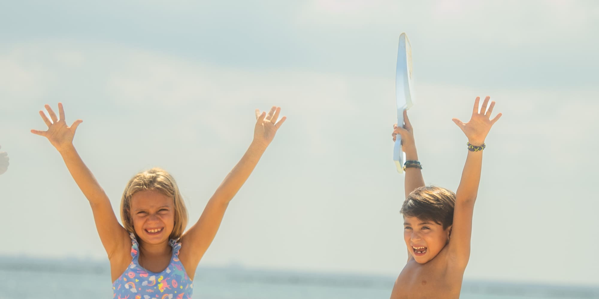 a boy and girl sitting on sand with sandcastles