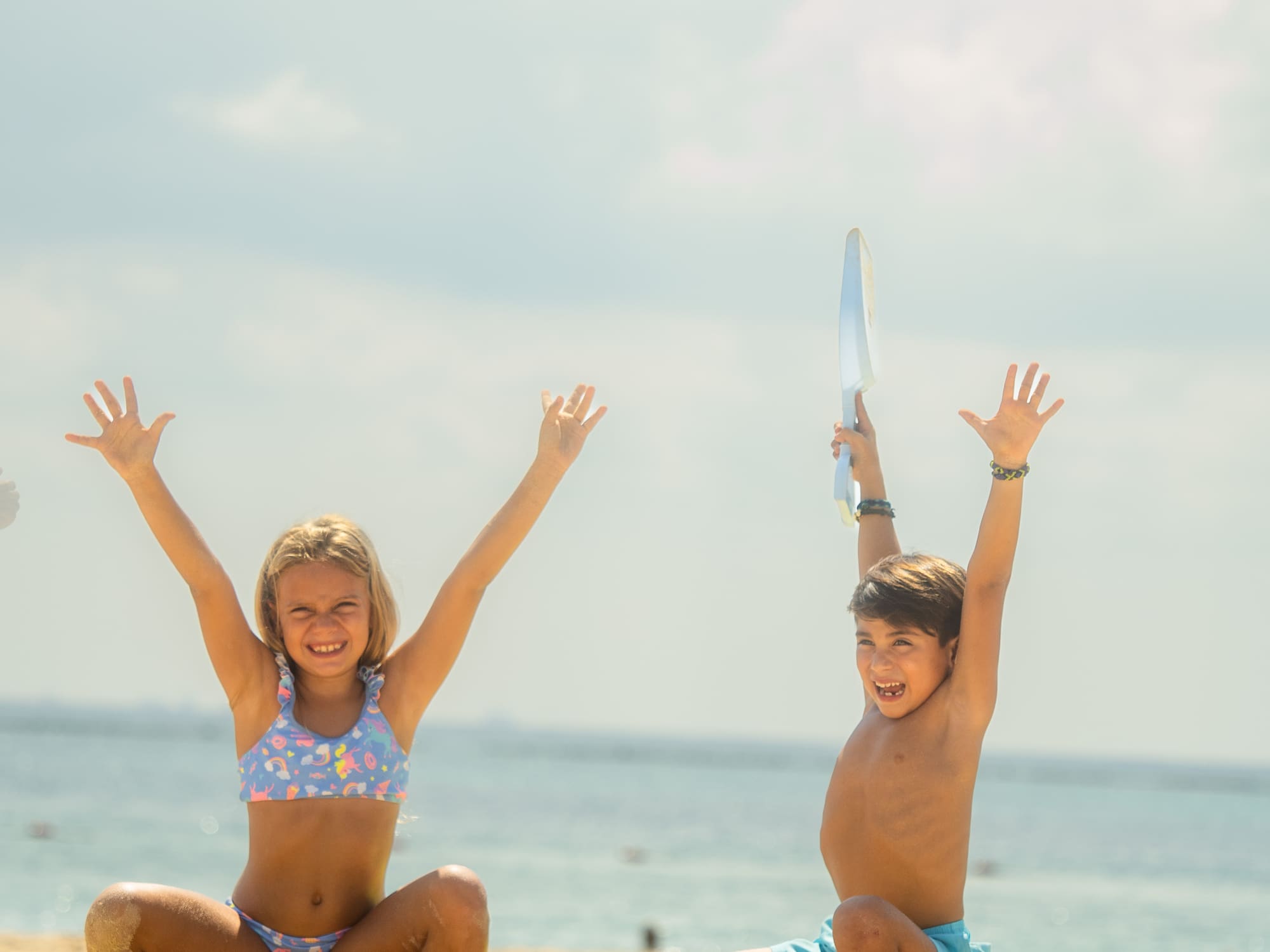 a boy and girl sitting on sand with sandcastles