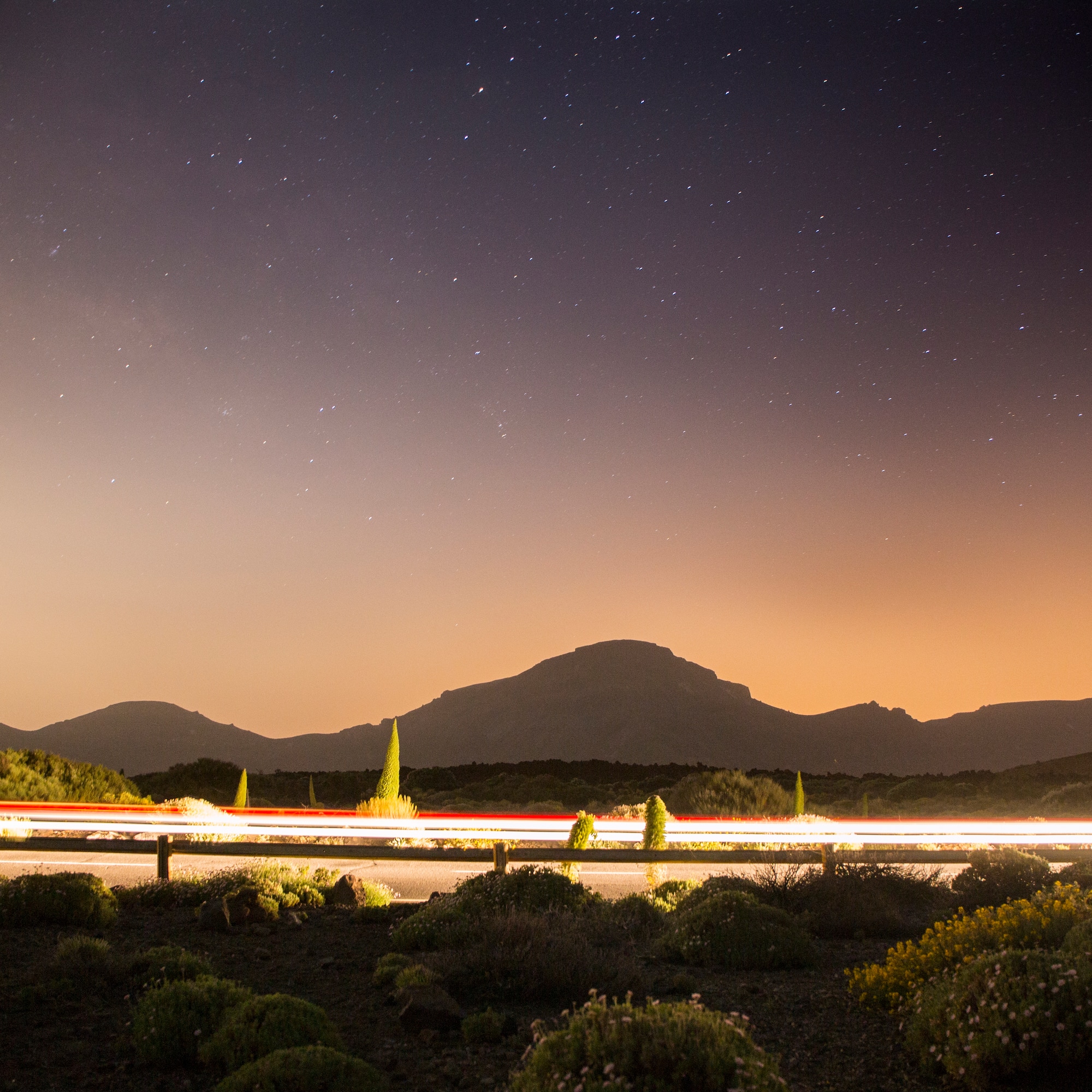 a road with lights on it and mountains in the background