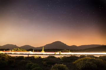 a road with lights on it and mountains in the background