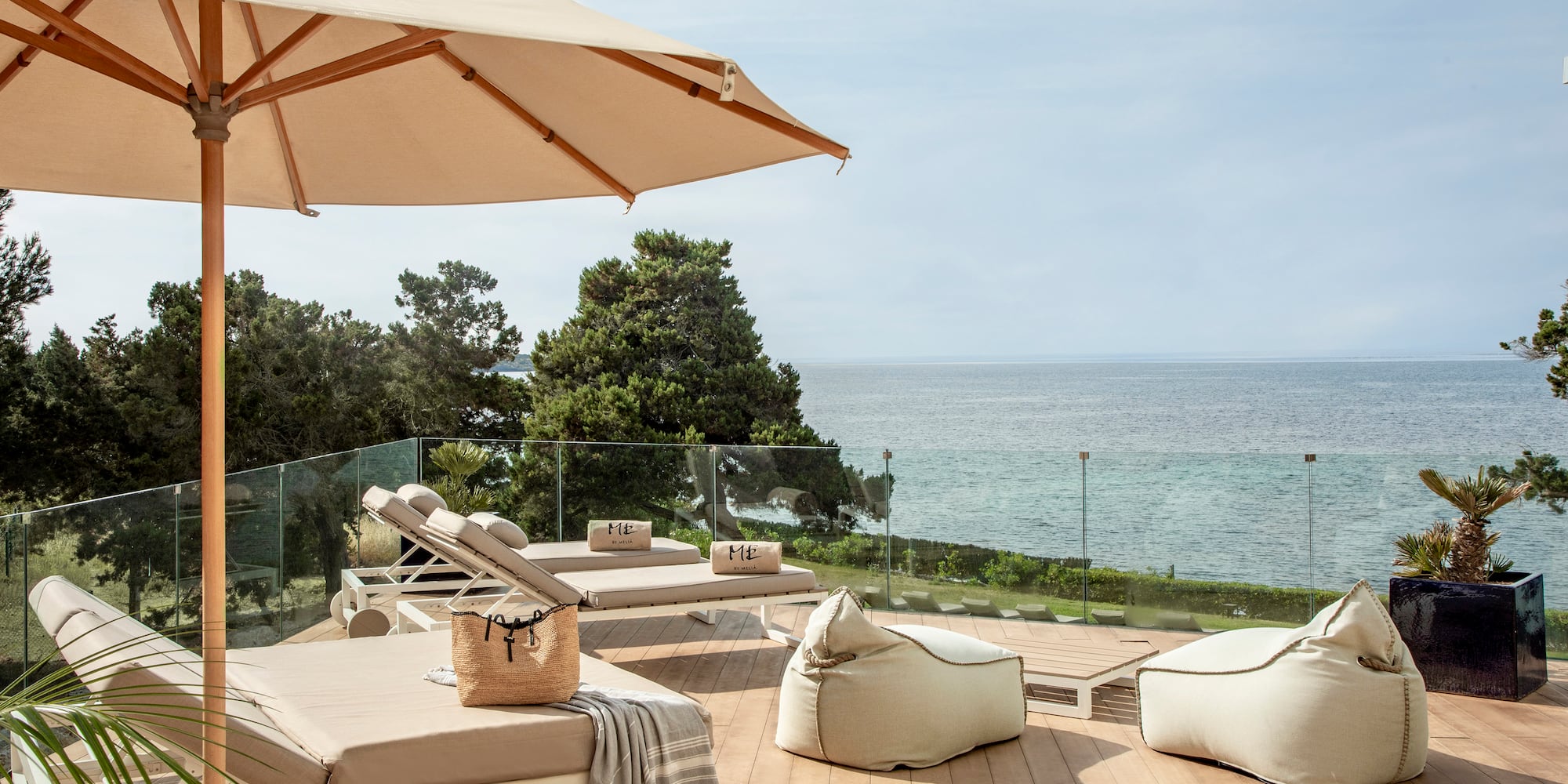 a deck with chairs and umbrellas and a large umbrella overlooking the ocean