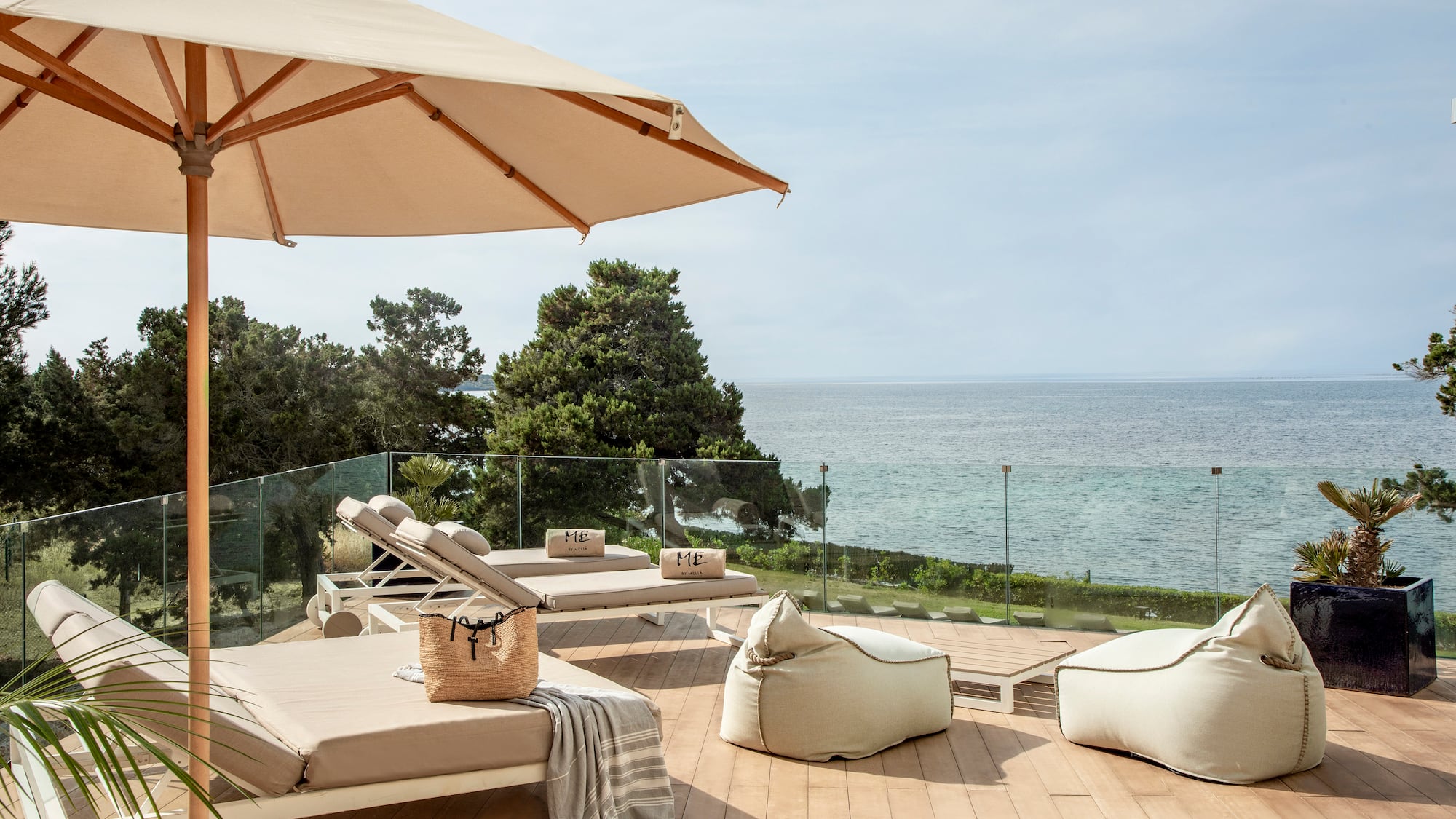 a deck with chairs and umbrellas and a large umbrella overlooking the ocean