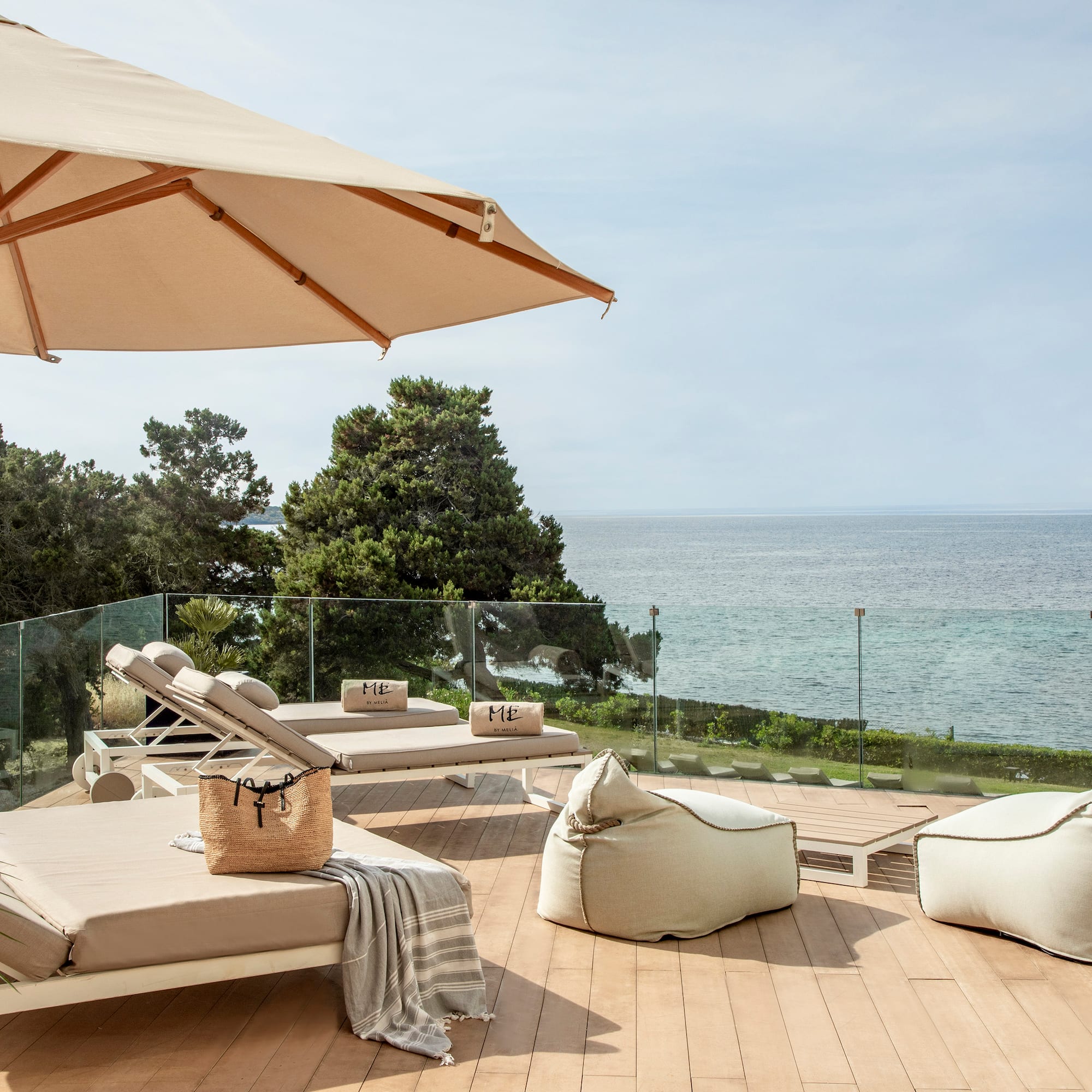 a deck with chairs and umbrellas and a large umbrella overlooking the ocean