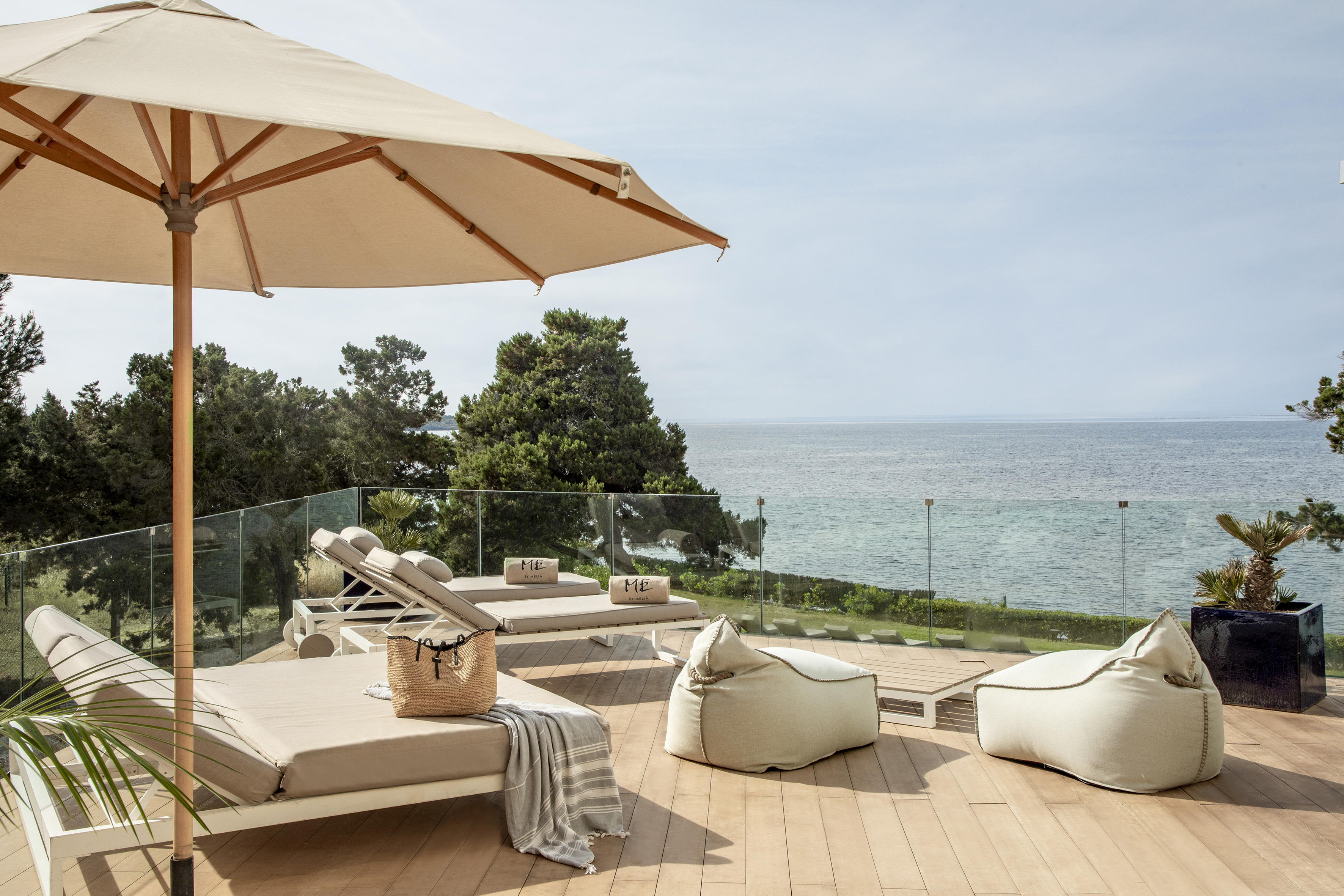 a deck with chairs and umbrellas and a large umbrella overlooking the ocean