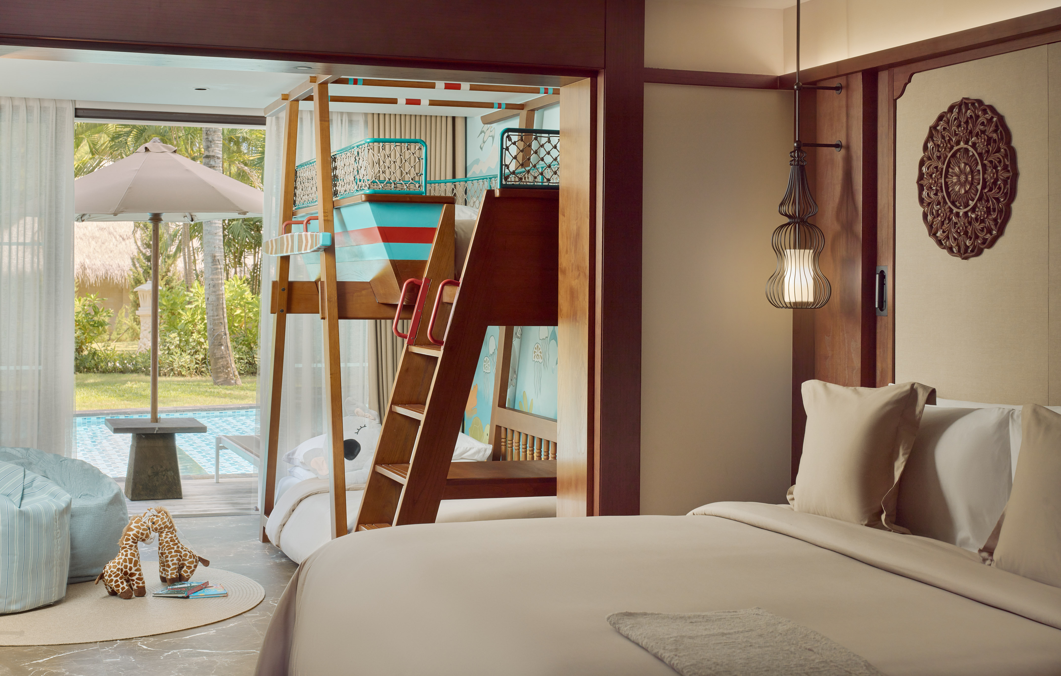 Luxury family hotel room with bunk beds, main bed, and tropical pool view.