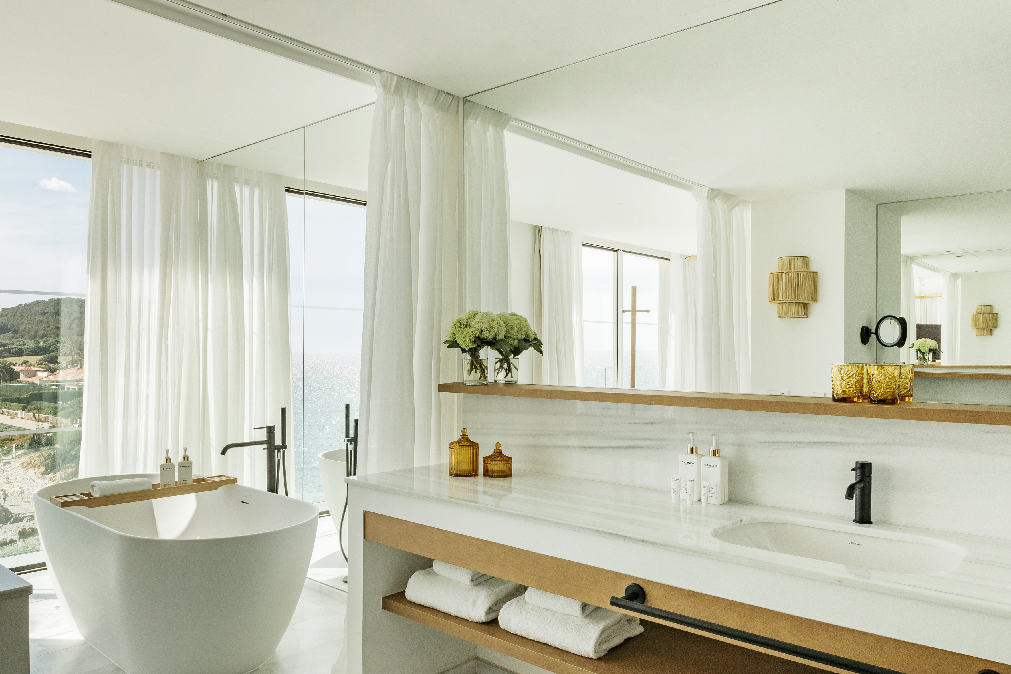Luxury bathroom with freestanding tub, ocean view, and marble vanity.