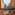 Resort balcony with sea view, palm trees, historic tower, and terracotta architecture.