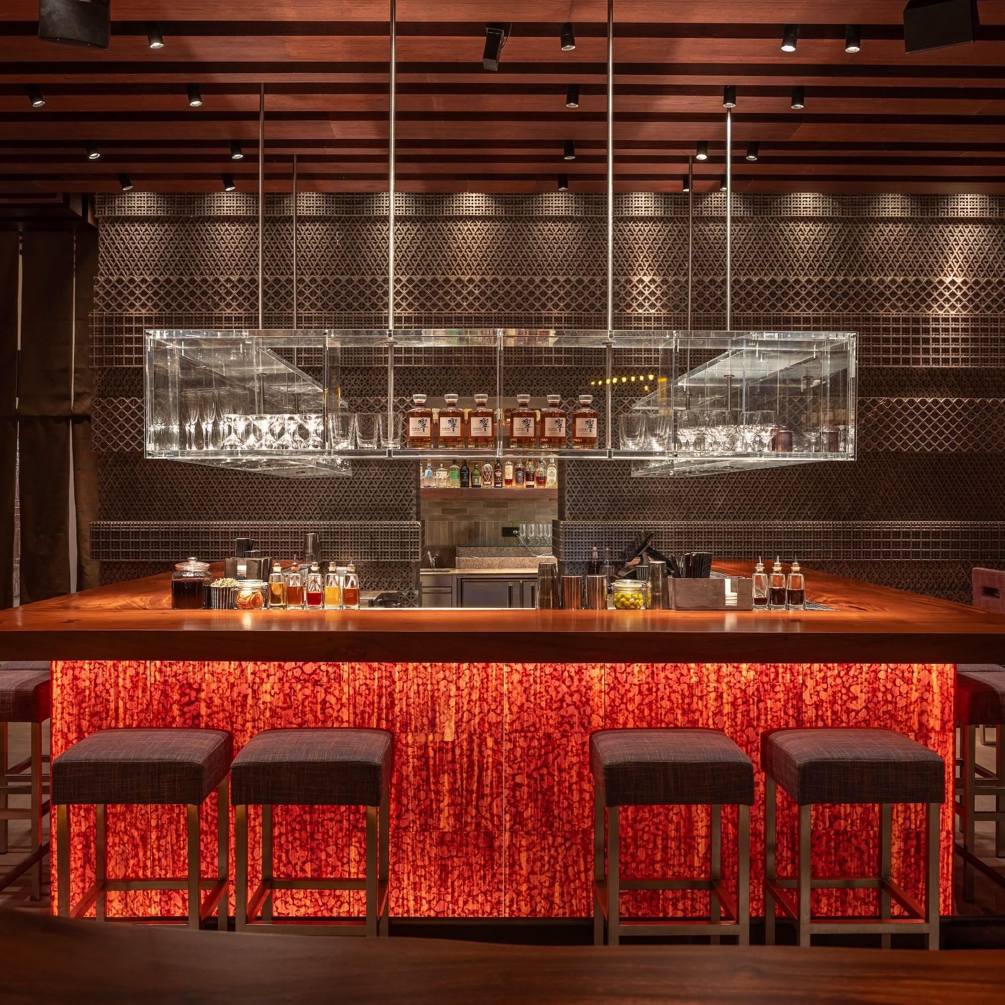 a bar with stools and bottles on the counter