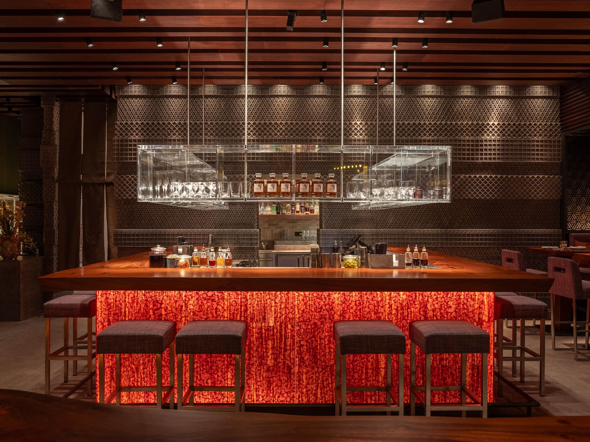 a bar with stools and bottles on the counter
