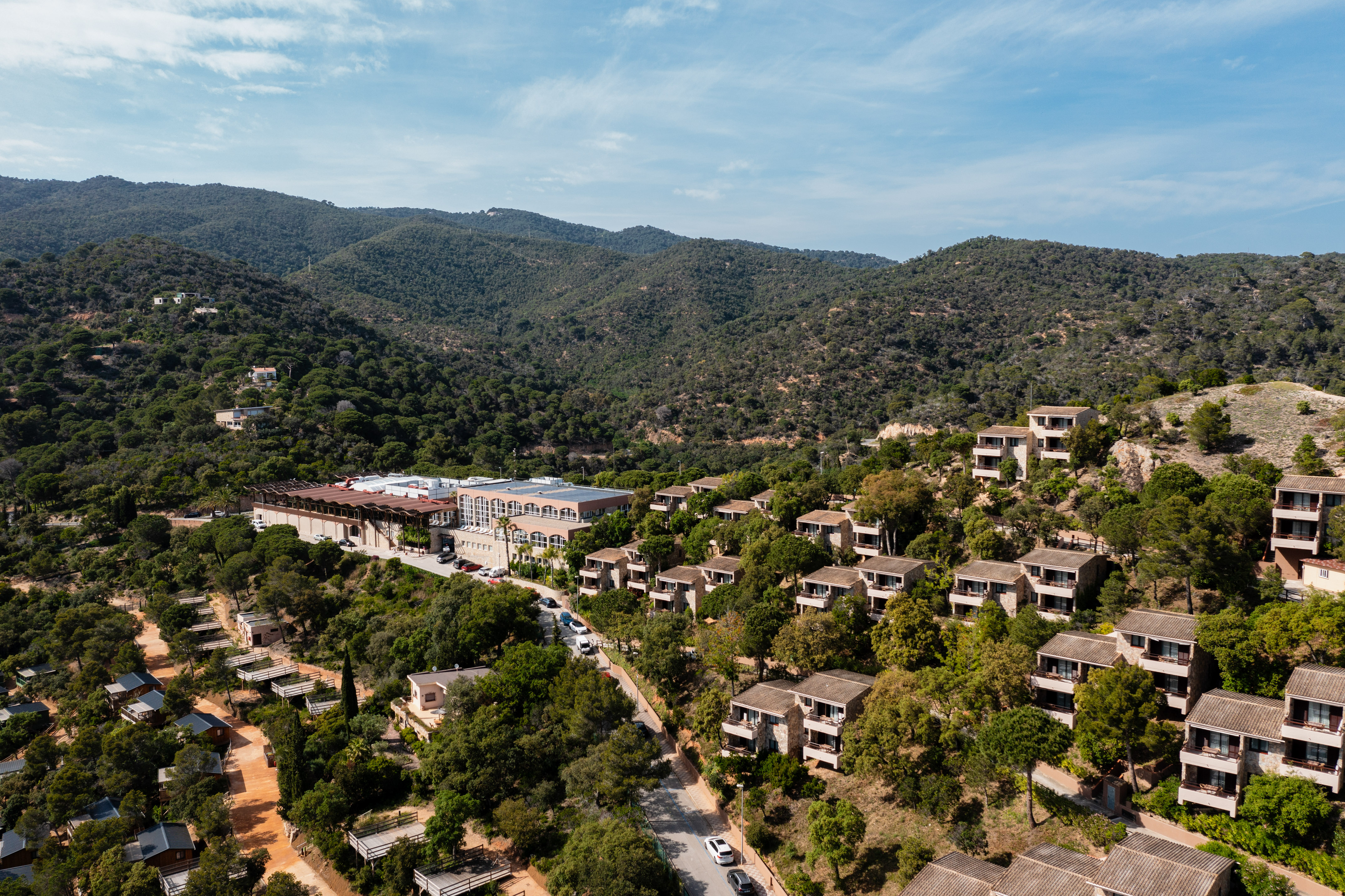 Aerial view of mountain resort villas and hotel on forested hills.