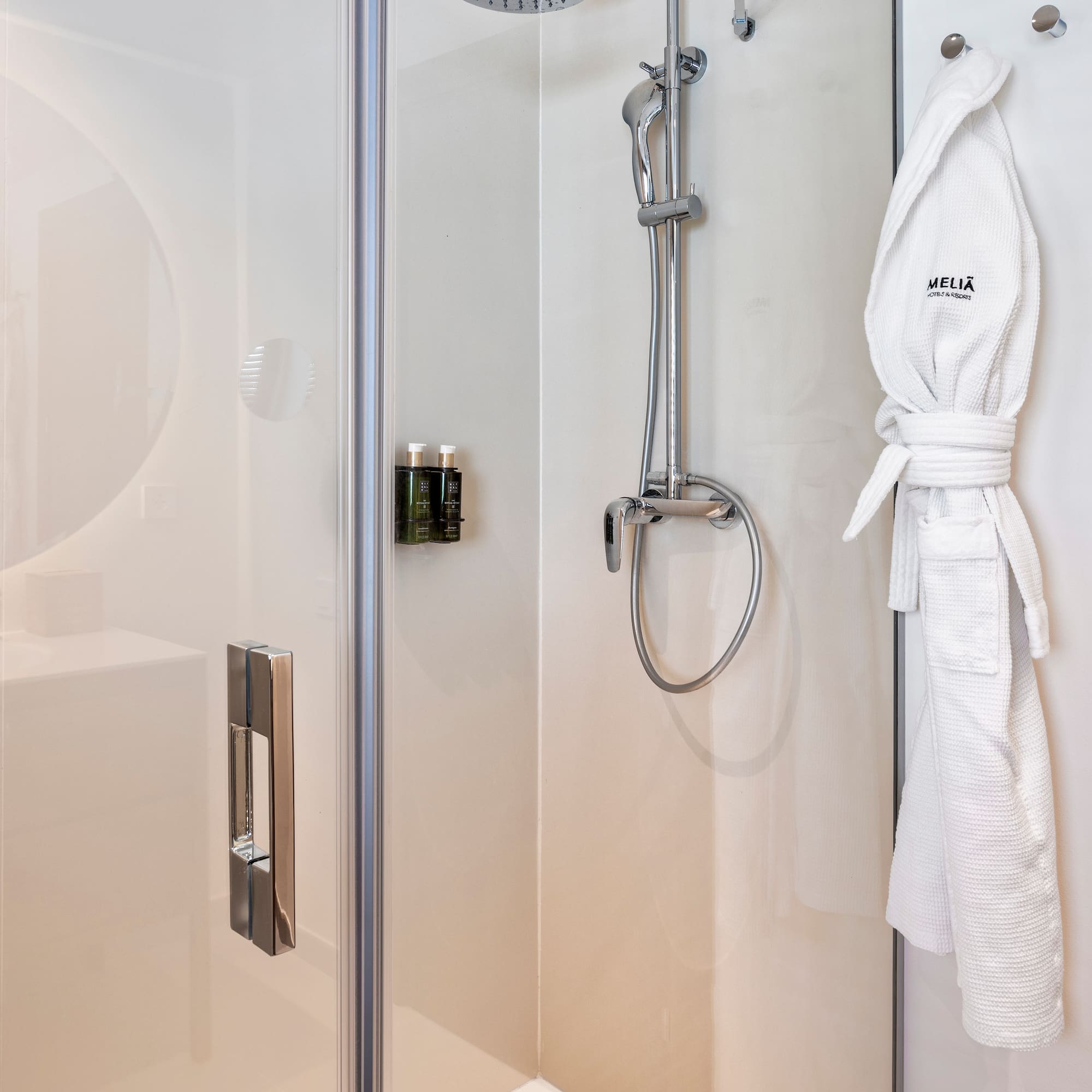 a shower with a white robe on a hook