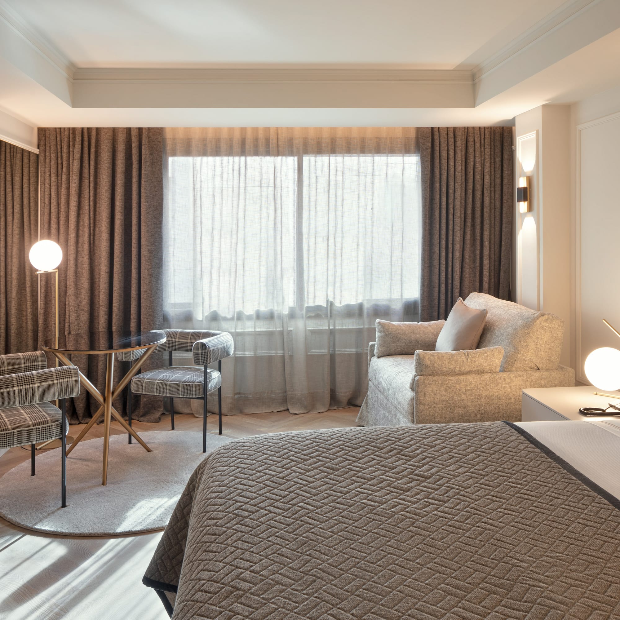 Habitación de hotel moderna: cama, zona de estar, mesa, sillas y ventanal.