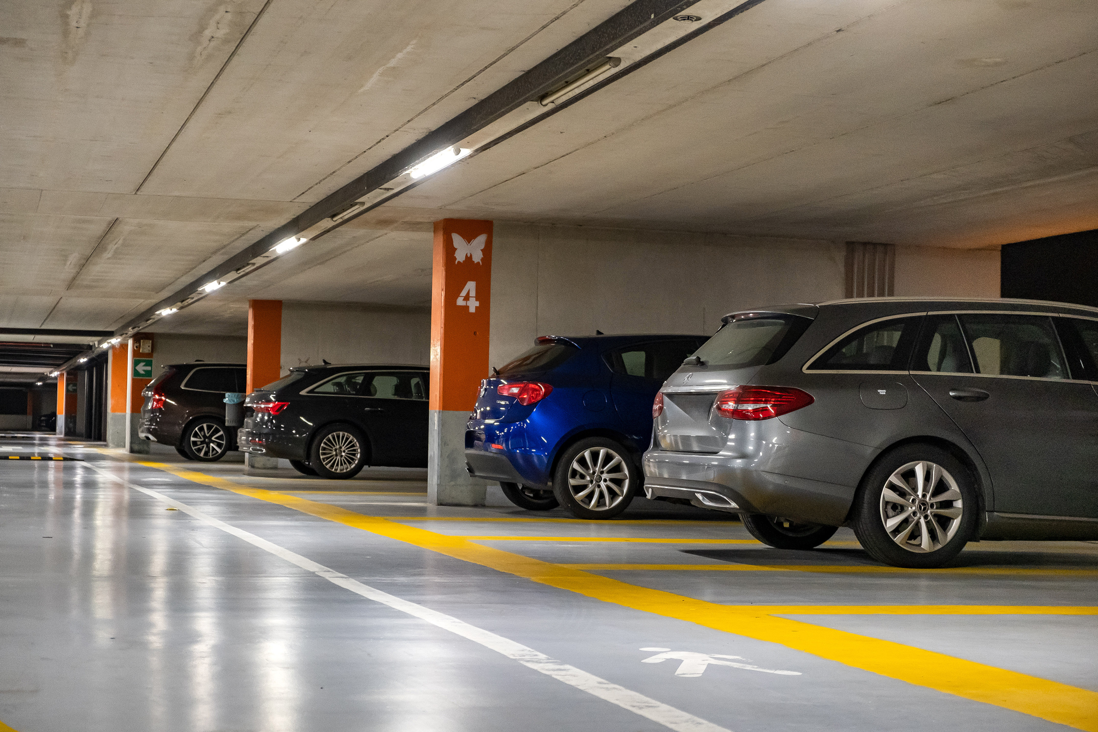 Underground parking garage with cars parked, yellow lines, and level 4 pillar.