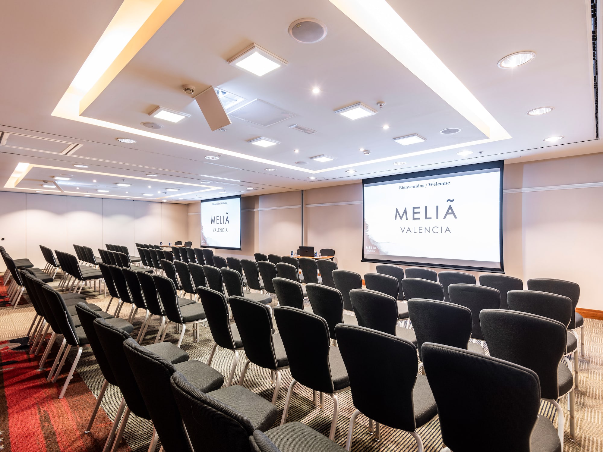 a room with rows of chairs and a projector screen