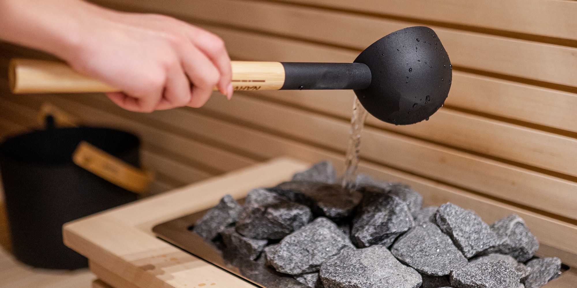 a person pouring water into a hot sauna