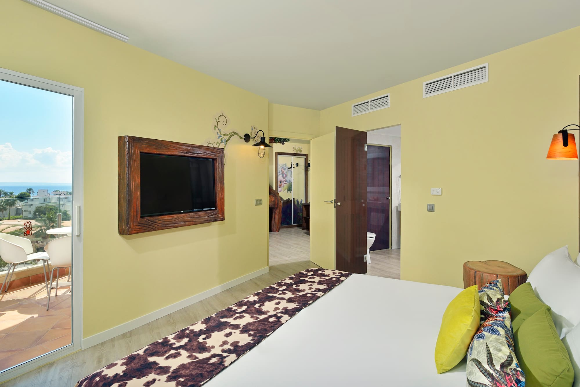 Modern hotel bedroom with ocean view balcony and cowhide bed runner.